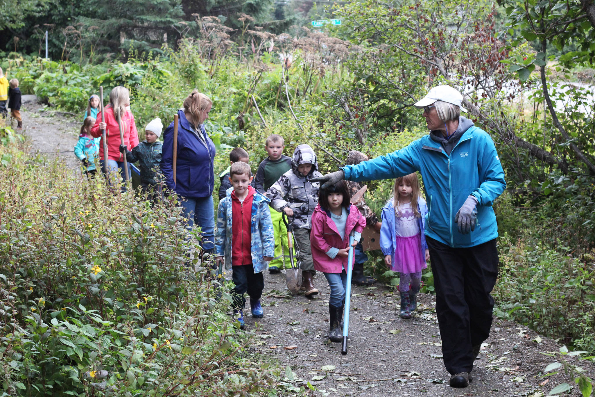 Deb Lowney leads a group of Paul Banks Elementary students along a recently-completed train at Karen Hornaday Park on Thursday, Sept. 7, 2017 in Homer, Alaska. The kids volunteered to transplant pine trees from a nearby street to the trails to help diversify the plant life in the park. (Photo by Megan Pacer/Homer News)