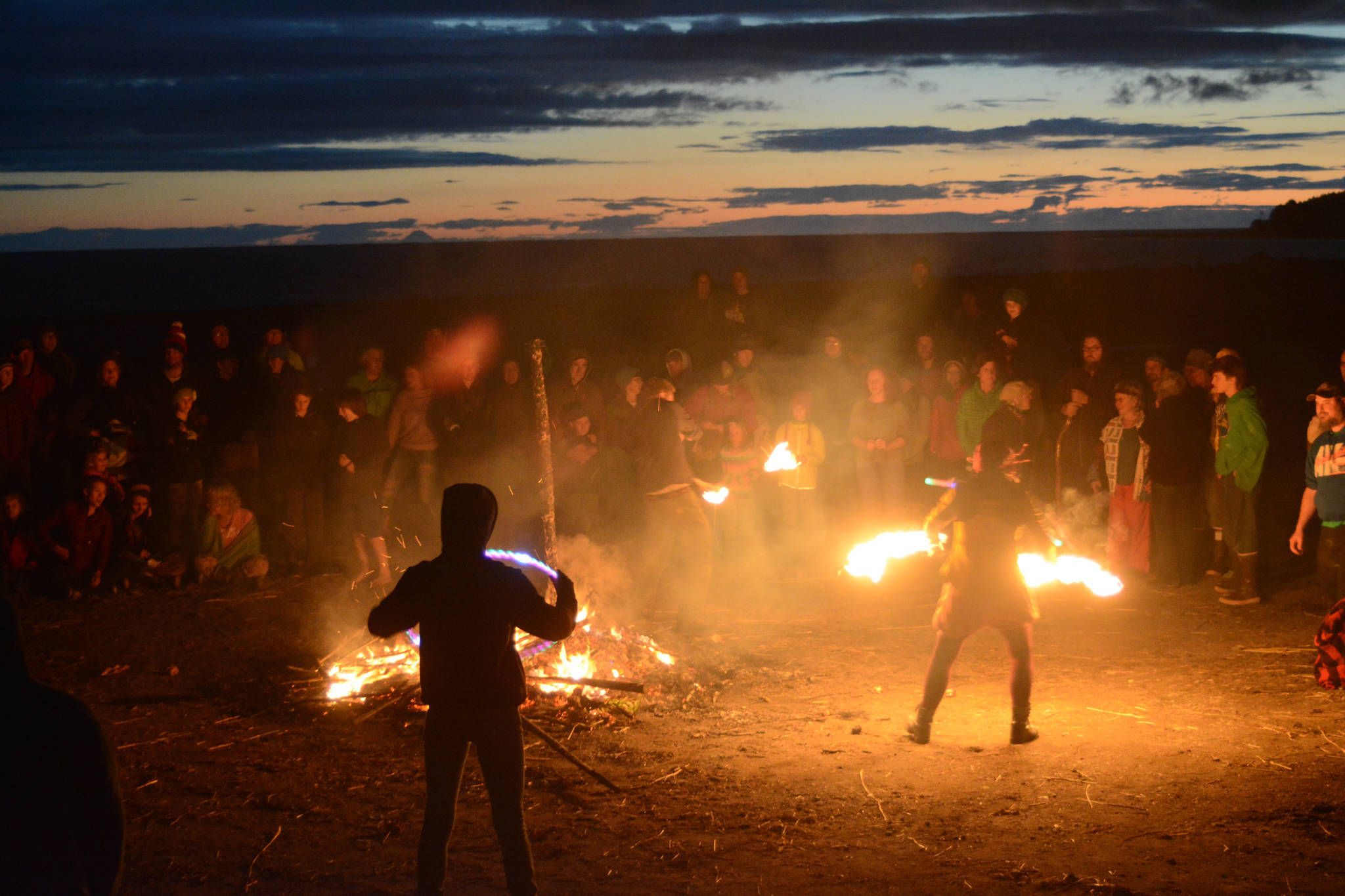 Revelers spin poi at Shine, the 2017 Burning Basket, as it burns on Sunday, Sept. 10, 2017 at Mariner Park on the Homer Spit. (Photo by Michael Armstrong, Homer News)