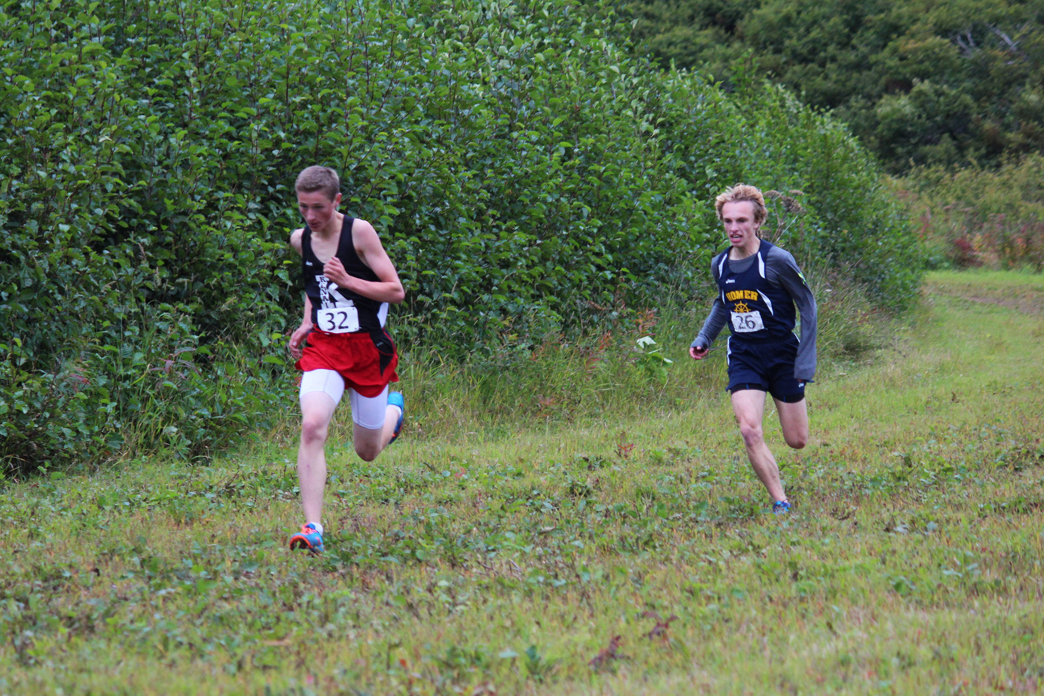 Kenai Central High School runner Maison Dunham beats Homer’s Jacob Davis to the finish line of the varsity boys race at the Kenai Peninsula Borough Cross Country Running Championships on Tuesday, Sept. 12, 2017 at the Lookout Mountain Trails near Homer, Alaska. Dunham took first for the varsity boys and Davis came in second. (Photo by Megan Pacer/Homer News)