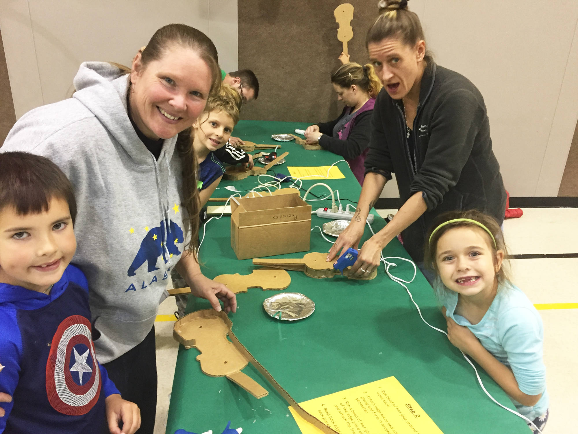 Quintin Stover and his grandmother (left) and Aviana Flyum with her mother (right) create violins out of cardboard Wednesday, Sept. 13, 2017 at Paul Banks Elementary School in Homer, Alaska. (Photo courtesy Wendy Todd)