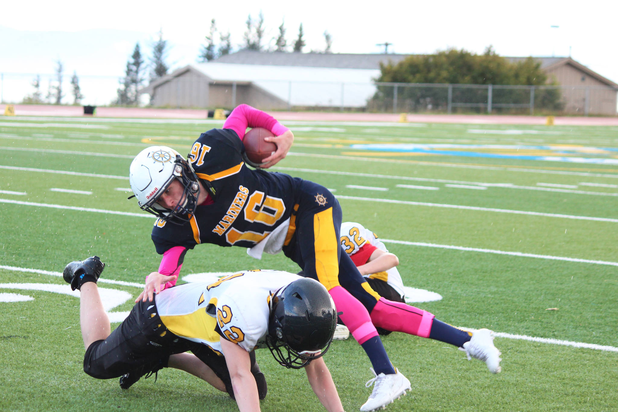 Homer senior Justin Sumption is taken down by Cougars sophomore Antonin Murachev (22) and freshman Markian Reutov (32) during their game Friday, Sept. 29, 2017 at the Mariner field in Homer, Alaska. The Mariners topped the Cougars 53-0. (Photo by Megan Pacer/Homer News)