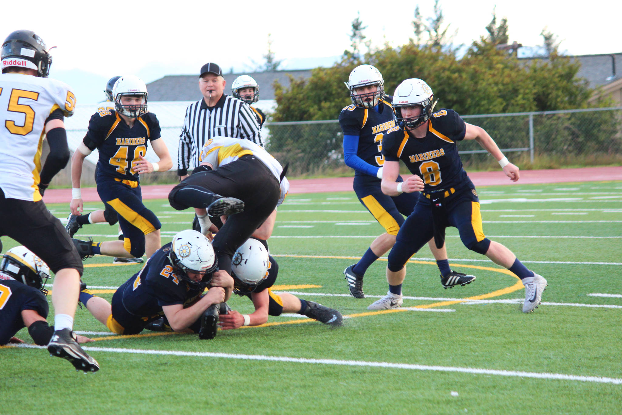 Two Homer Mariner varsity football team members grab onto the leg of David Sanarov, a senior player for the Head of the Bay Cougars, as he runs the ball during their Friday, Sept. 2017 game at the Mariner field in Homer, Alaska. Homer came out on top 53-0. (Photo by Megan Pacer/Homer News)