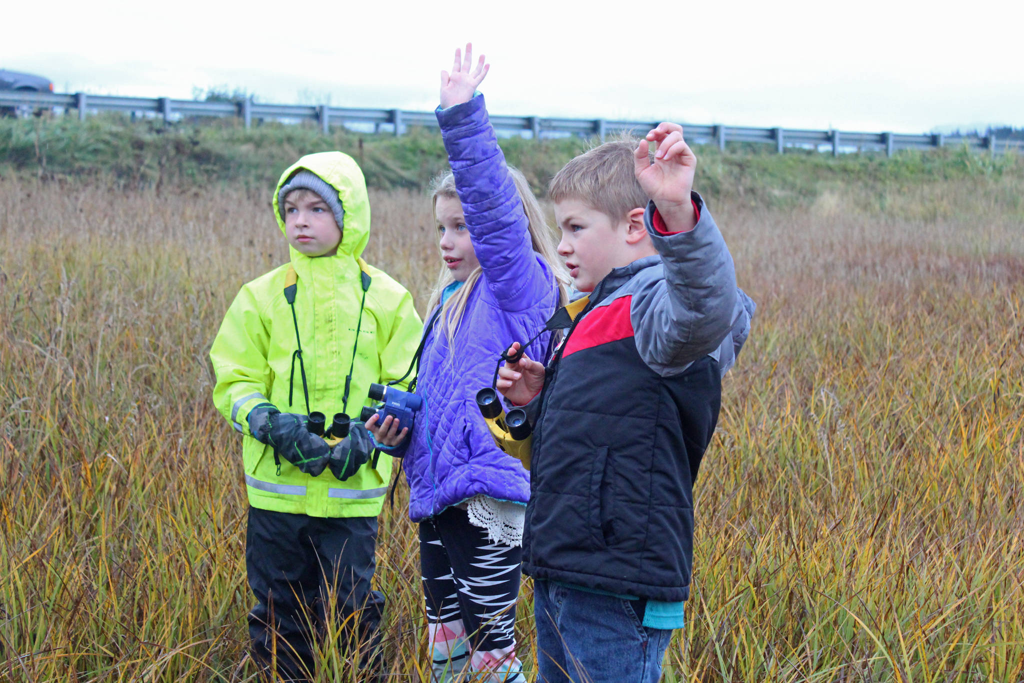 Paul Banks Elementary students Gabe Stanislaw (left), Tatum Kirtley (center) and Isaiah Mann (right) raise their hands to answer a questions during a field trip to the Beluga Slough on Thursday, Sept. 28, 2017 in Homer, Alaska. (Photo by Megan Pacer/Homer News)