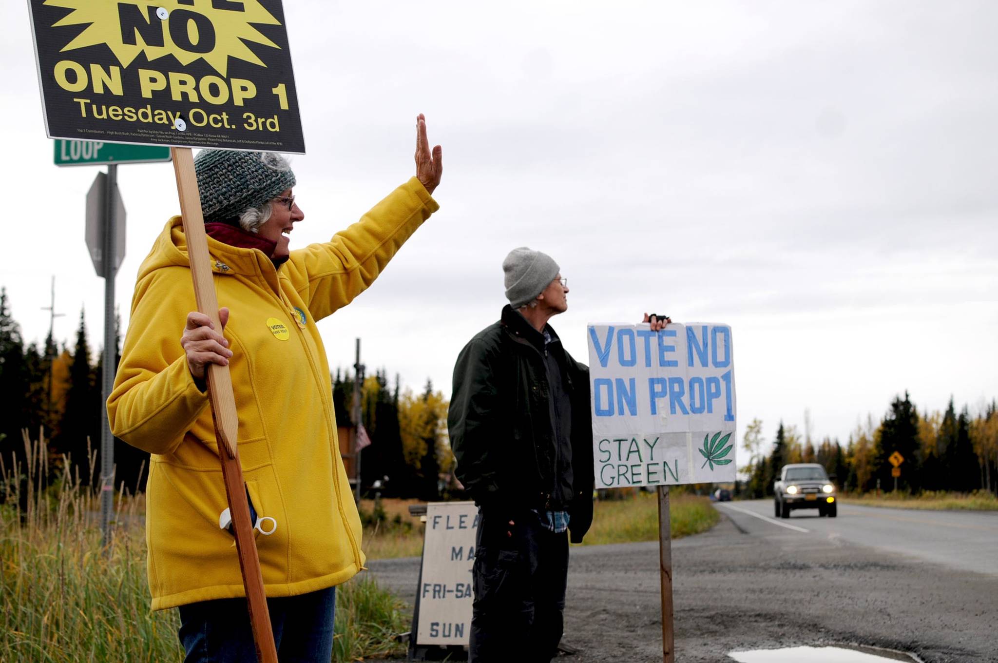 Ann Fraser (left) and Steve Waldron (right), both of Kasilof) wave signs opposing Kenai Peninsula Borough Proposition 1 on the corner of Pollard Loop and the Sterling Highway on Tuesday in Kasilof. Voters in Kasilof and the other unincorporated communities of the borough voted Tuesday on Proposition 1, which asked whether commercial cannabis operations should be legal in the borough outside the city limits. (Photo by Elizabeth Earl/Peninsula Clarion)