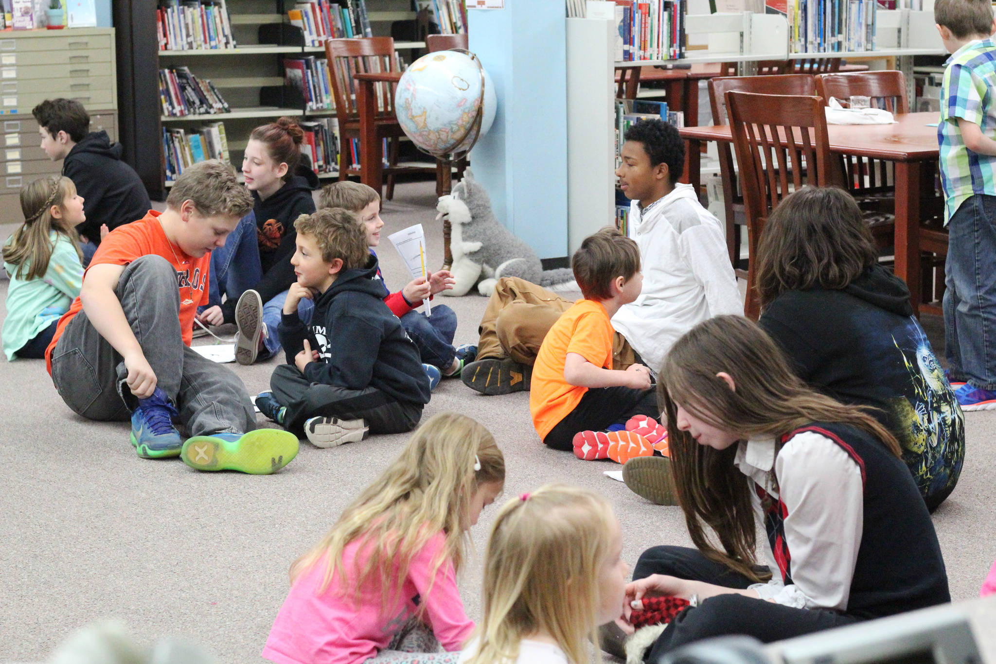 Eighth graders from Homer Middle School and first graders from Paul Banks Elementary debrief after working together on a project on sound during a lesson at the middle school Tuesday, Oct. 24, 2017 in Homer, Alaska. The lesson was organized through a mentorship program recently finalized between teachers at the two schools in which the younger students are paired with and learn from the older. (Photo by Megan Pacer/Homer News)