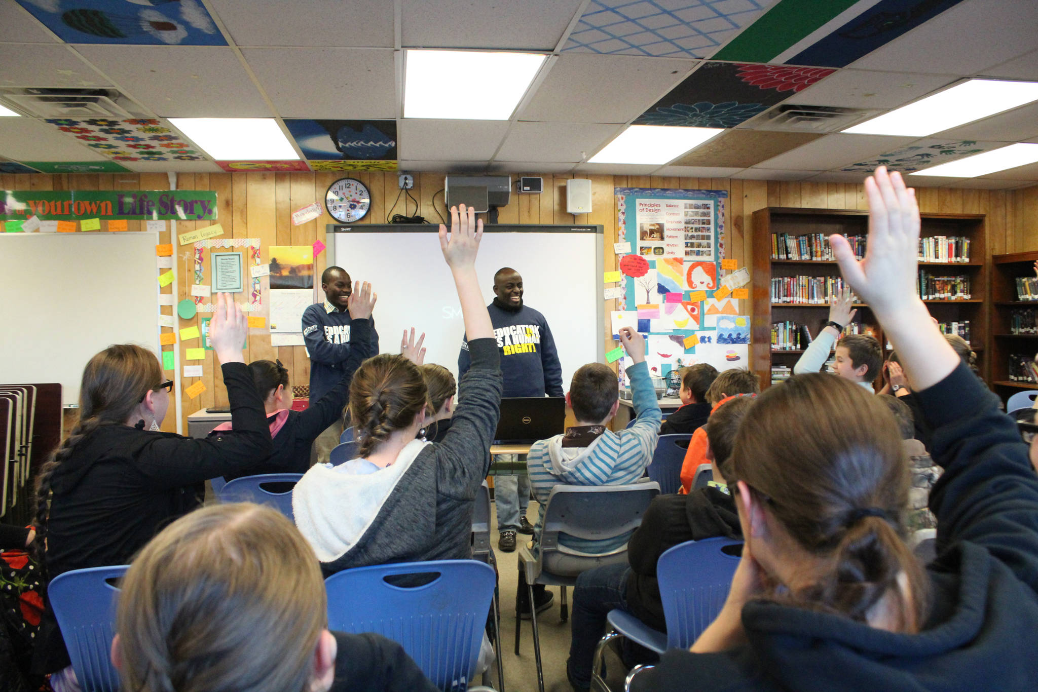 Human rights lawyer and Kenya native Chris Mburu, right, and Kimani Nyambura, left, laugh as the majority of a room full of Razdolna students raise their hand to respond to the question of how many of them have the last name Basargin, during a presentation Friday, Nov. 17, 2017 at the school in Razdolna, Alaska. Mburu, who started a foundation to put Kenyan children through school after being sponsored himself, gave presentations to several Kenai Peninsula schools this week along with Nyambura, one of the students who has been able to go to school thanks to the foundation. (Photo by Megan Pacer/Homer News)