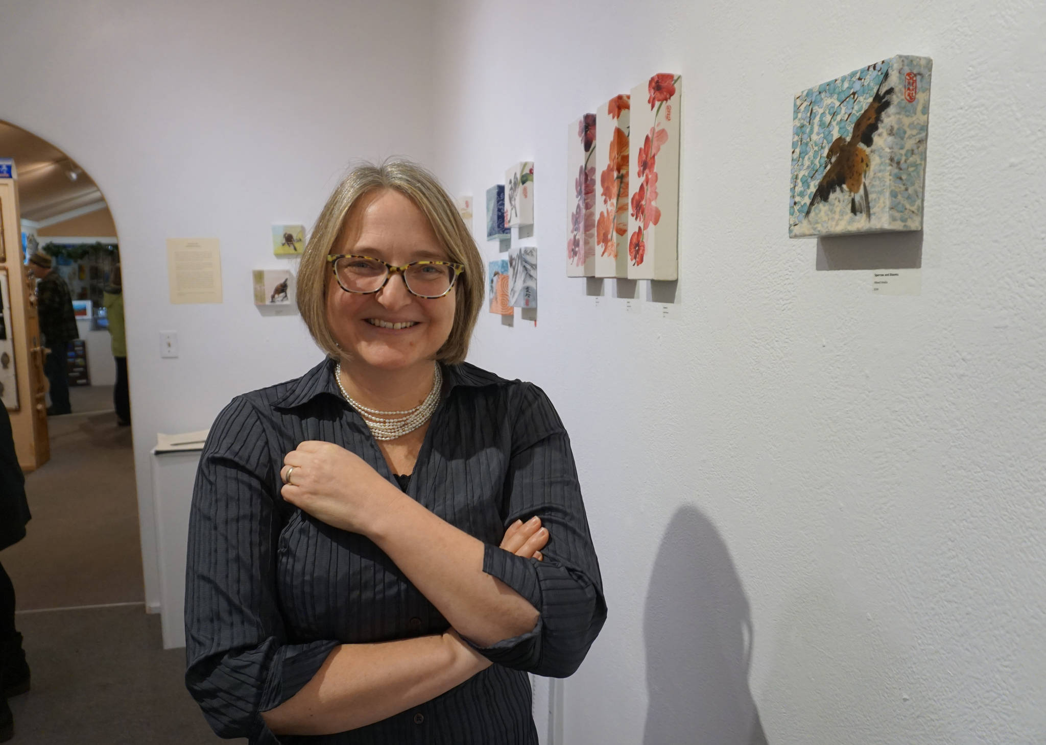 Sharlene Cline greets visitors at her First Friday opening on Friday, Dec. 1, 2017, at her show of collages using Chinese brush painting and other media at Ptarmingan Arts in Homer, Alaska. (Photo by Michael Armstrong, Homer News)