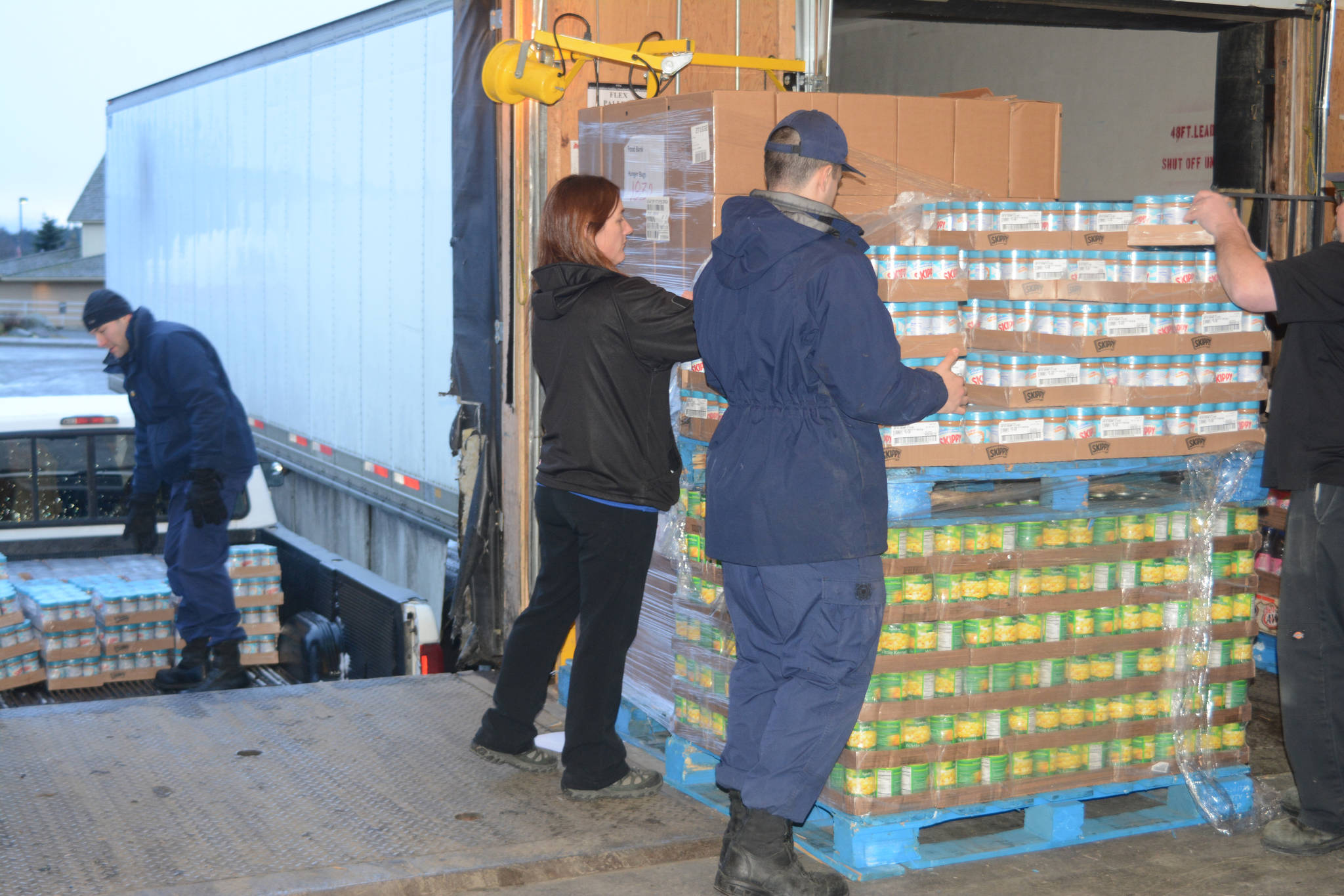 U.S. Coast Guard Cutter Naushon crew member Jordan Dorchin, right, helps Homer Safeway assistant store manager Tiffany Biggs, center, load Hunger Bag food onto a truck as his fellow crew member James Bannon, left, packs the truck Tuesday, Dec. 5, 2017. The Coast Guard members delivered food to the Homer Community Food Pantry Tuesday morning that had been purchased by Safeway customers as part of its Hunger Bag project. Store Manager Bob Malone said about 1,300 bags at $10 each had been sold at the Homer store since Nov. 1. Through a national program, Safeway sells the bags and donates food to charities chosen by local stores. Pallets of food are organized at the Anchorage warehouse and sent to Homer. “This year, from what I understand, the need is more than normal,” Malone said.