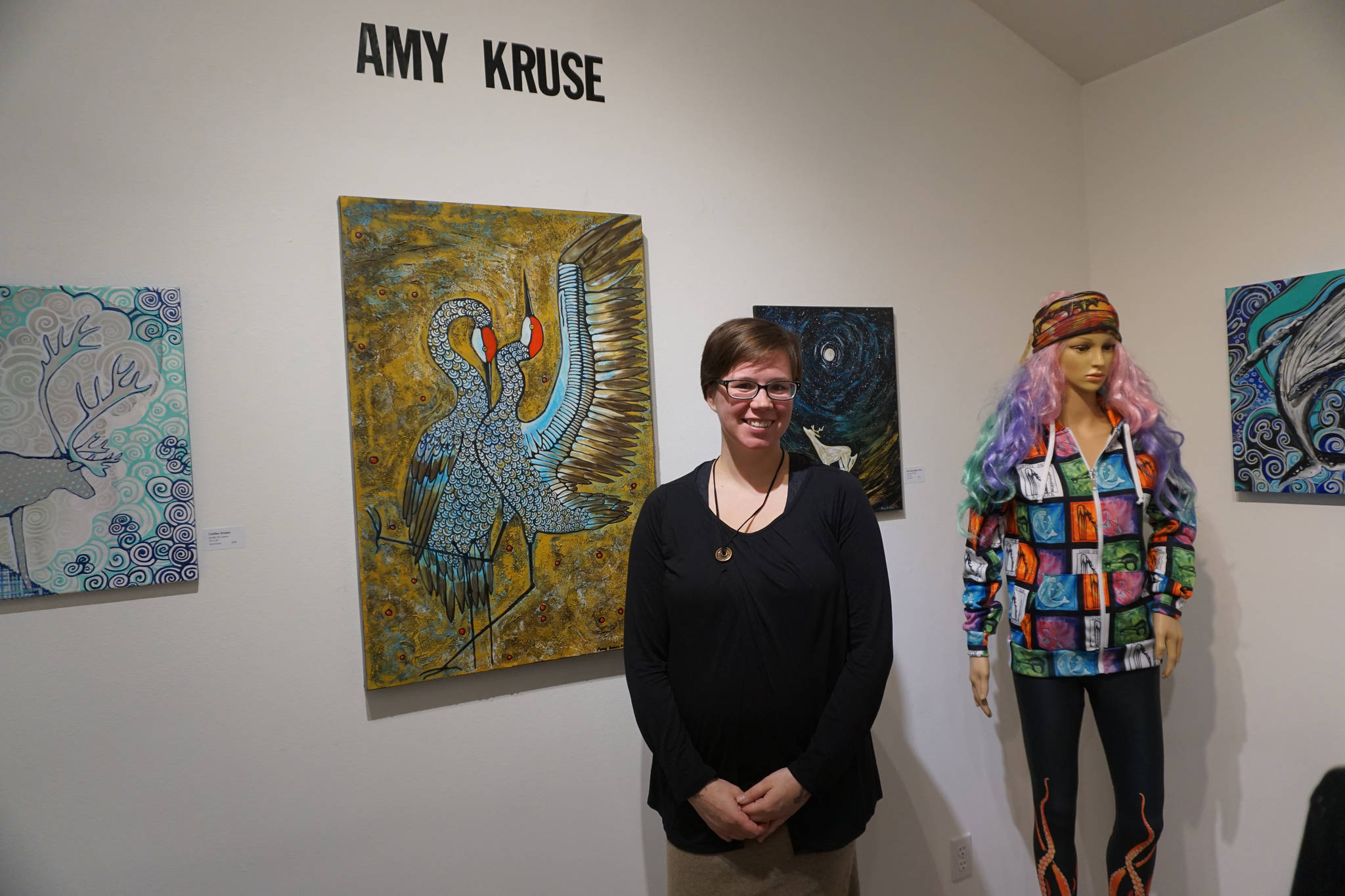 Amy Kruse poses for a photo at a First Friday reception on Dec. 1, 2017 at Fireweed Gallery in Homer, Alaska. Some of her fashion designs is on the mannequin at right. (Photo by Michael Armstrong, Homer News)