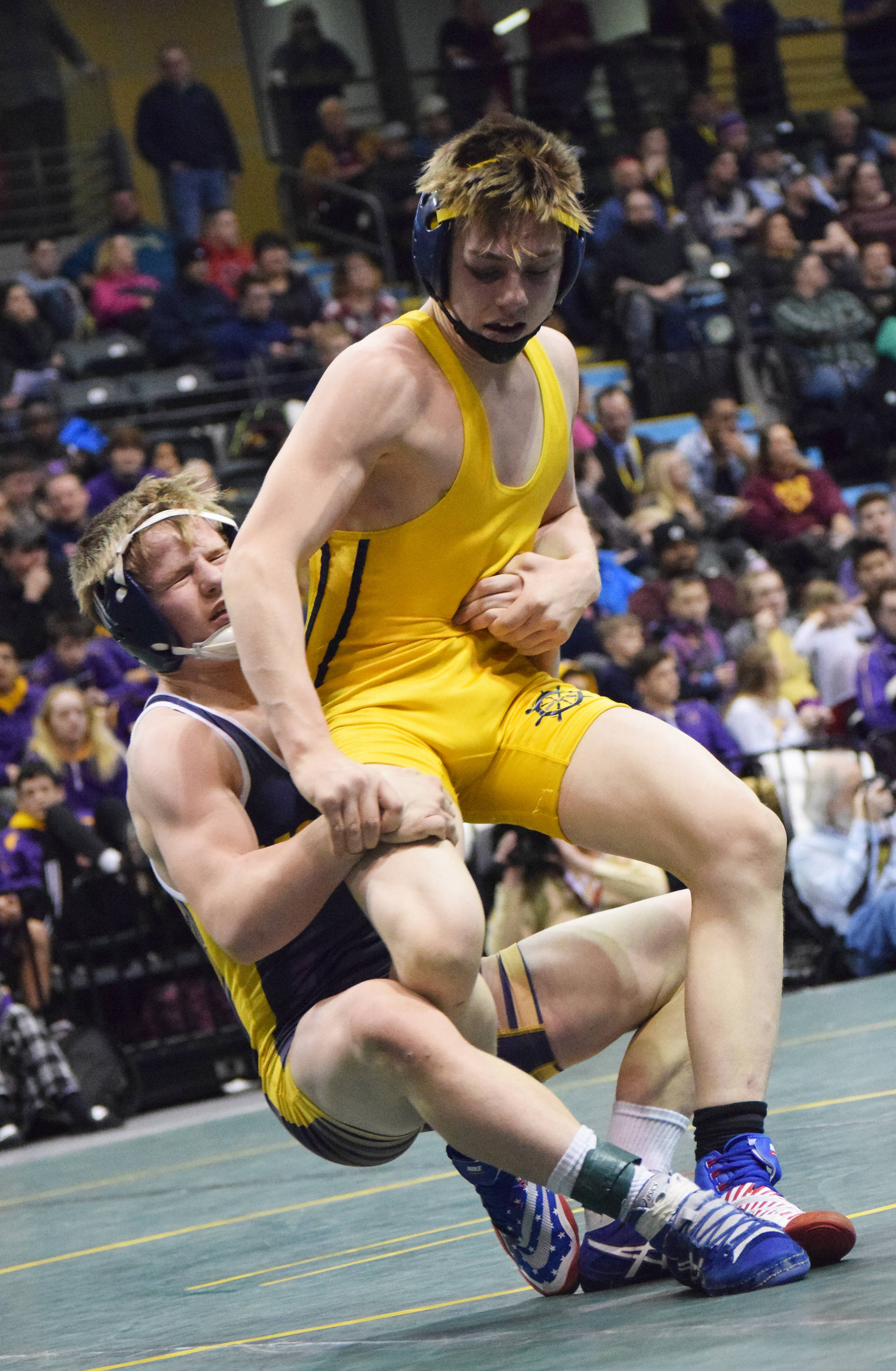 Monroe Catholic’s Riley Rust (left) takes down Homer’s Wayne Newman in the 126-pound final Saturday night at the Division II state wrestling championships at the Alaska Airlines Center in Anchorage. (Photo by Joey Klecka/Peninsula Clarion)