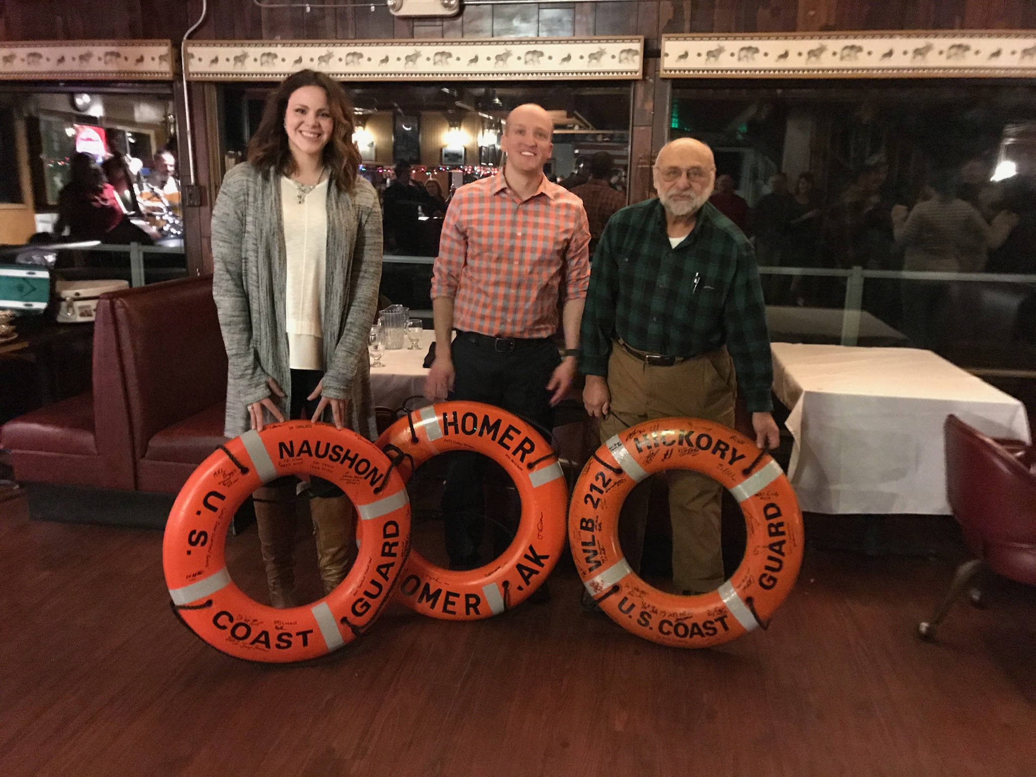 USCG Naushon and Hickory commanding officers present ship’s rescue rings for display in the Homer Elks Lodge dining room at a holiday party held for local Coast Guard on Dec. 14, 2017. Pictured left to right are Naushon Commander Lt. Lauren L. Milici, Hickory Commander Lt. Brent Mellen and Don Cotogno, Homer Elks Board Chairman. (Photo provided)