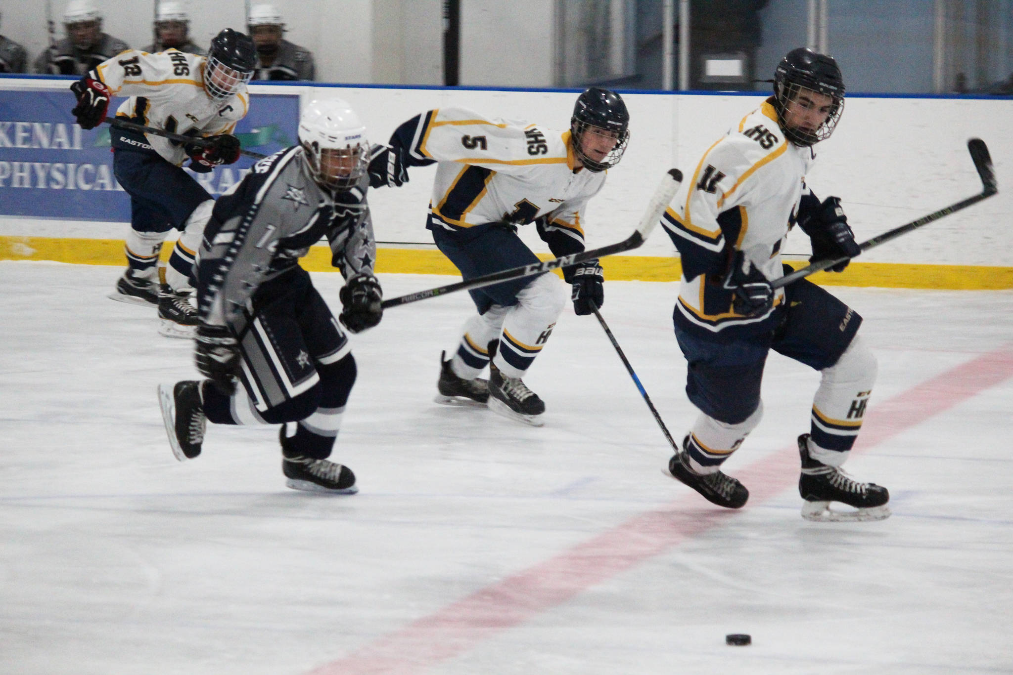 Homer hockey players Dimitry Kuzmin (12), Douglas Dean (5) and Charlie Menke (11) chase after the puck along with Soldotna’s Alex Montague during their game Tuesday, Jan. 16, 2018 at Kevin Bell Arena in Homer, Alaska. The Mariners beat the Stars 10-1. (Photo by Megan Pacer/Homer News)