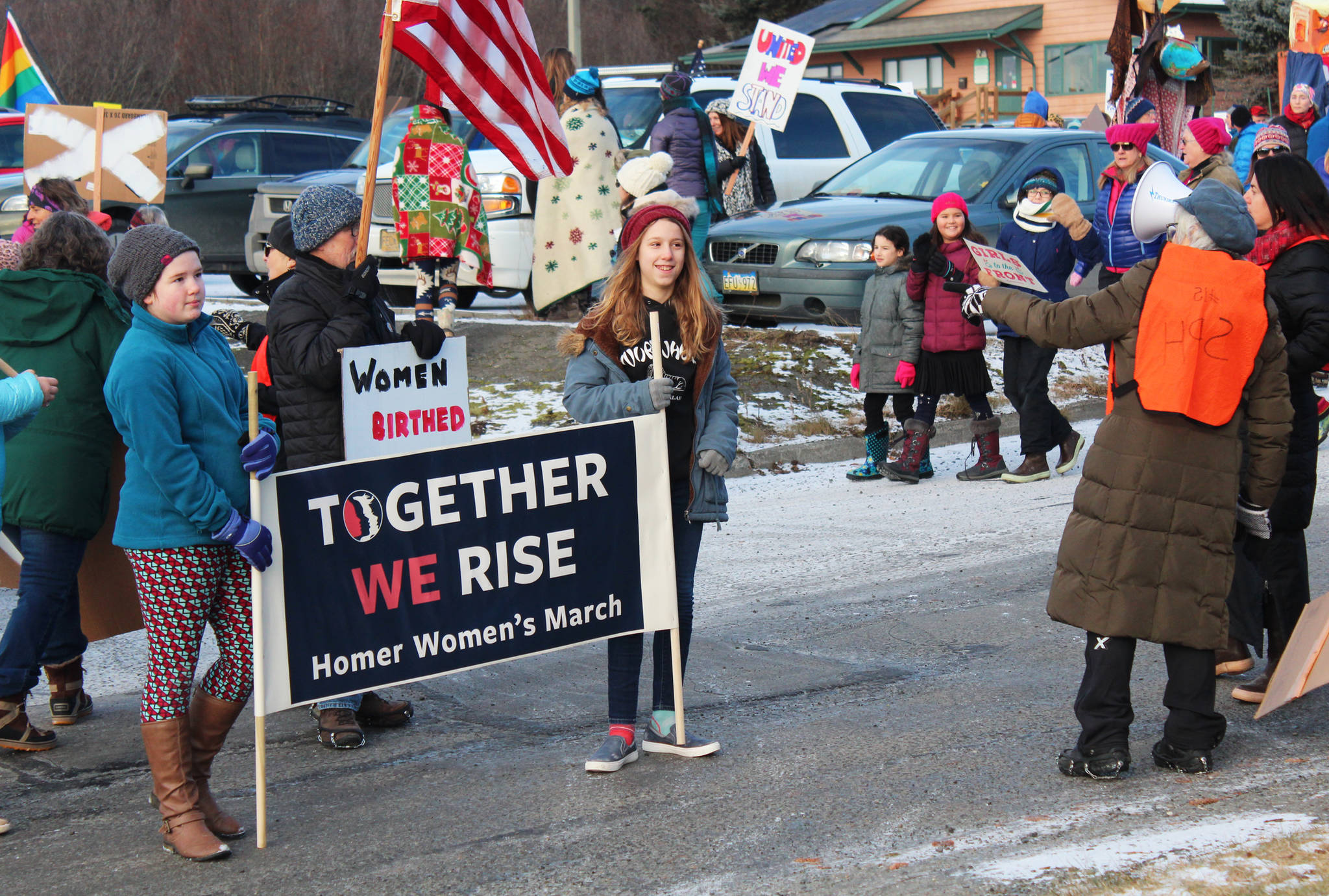 West Homer Elementary students Caitlin Smith (left) and Gillian Bremicker prepare to lead the Women’s March on Homer 2018 out of the HERC parking lot and down Pioneer Avenue on Saturday, Jan. 20, 2018 in Homer, Alaska. The pair said they asked for a sign to carry and were surprised and excited to be offered the lead banner. (Photo by Megan Pacer/Homer News)