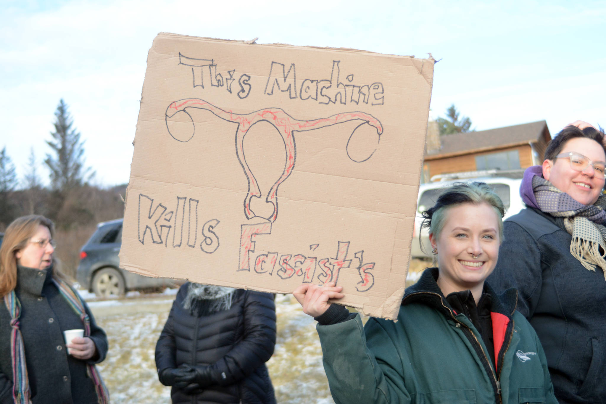 Ariel Gingrich holds a sign reading “This machine kills fascists” with a drawing of a woman’s reproductive system in the Homer March for Women on Saturday. The sign is a reference to a sticker musician Woody Guthrie put on his guitar in 1941 during World War II. About 700 people walked in the march along Pioneer Avenue on Jan. 20, 2018, in Homer, Alaska. The line of marchers extended from Main Street to Kachemak Way. (Photo by Michael Armstrong/Homer News)