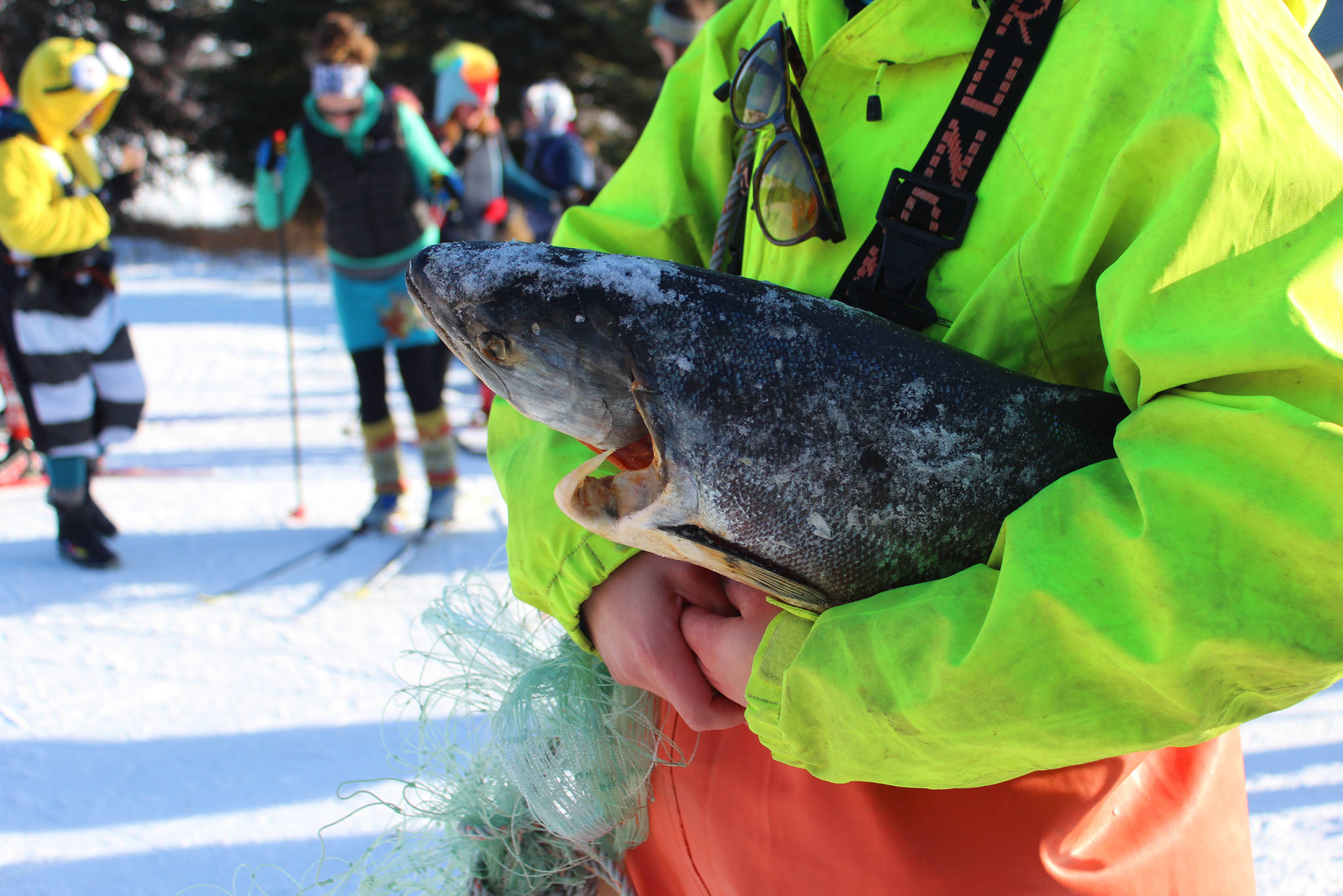 Claire Neaton holds a frozen salmon as part of the attached ensemble costume she and her friends wore to the 2018 Homer Ski for Women on Sunday, Feb. 4, 2018 at the Lookout Mountain Ski Trails. The ski is a fundraiser for Haven House, with prizes for the best costumes. (Photo by Megan Pacer/Homer News)
