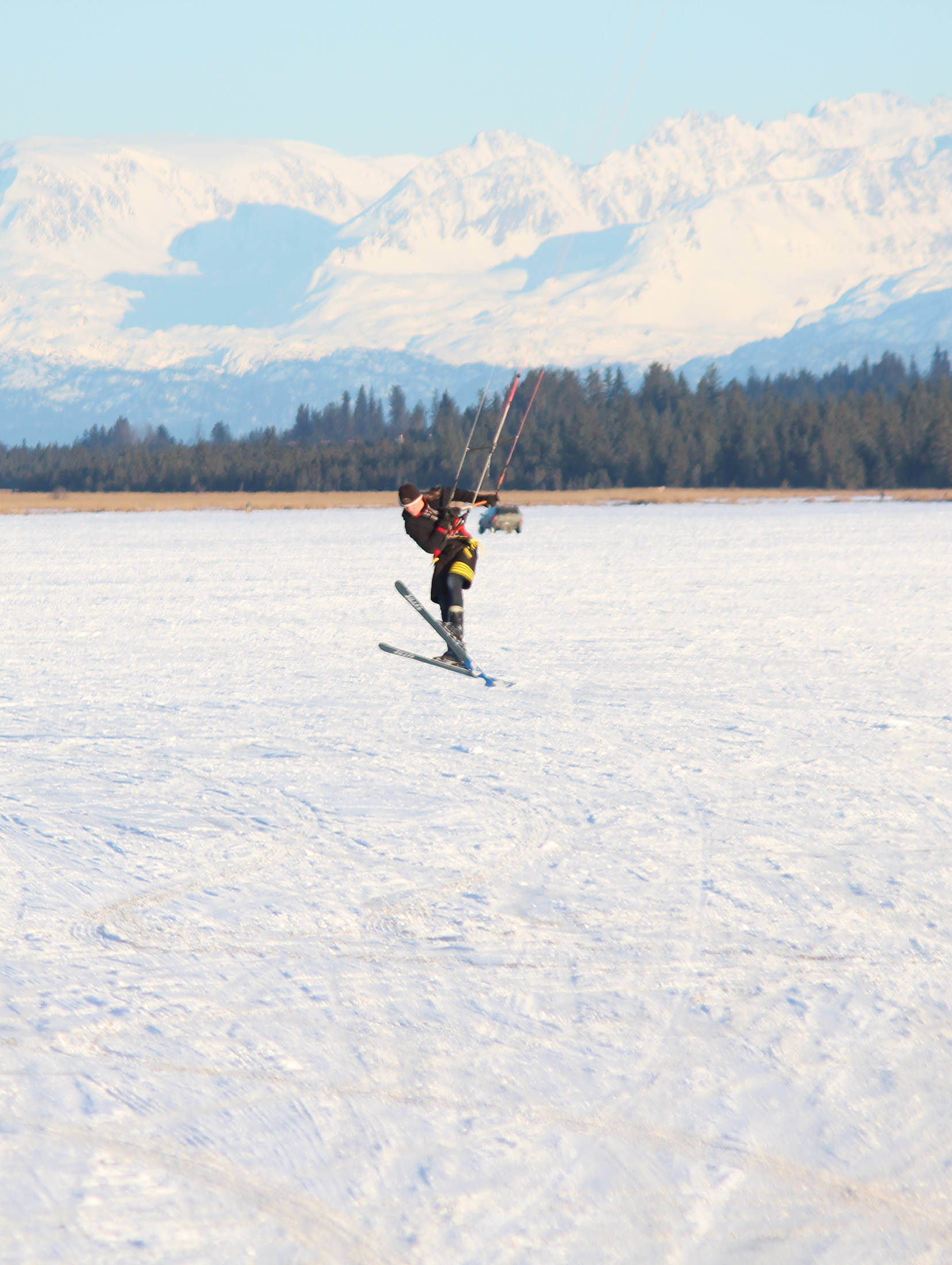 A man catches some air while snowkiting, or kite skiing, on Beluga Lake on Saturday, Feb. 3, 2018 in Homer, Alaska. Outdoor enthusiasts use the power provided by a large kite on a windy day to glide across snow or ice. (Photo by Megan Pacer/Homer News)