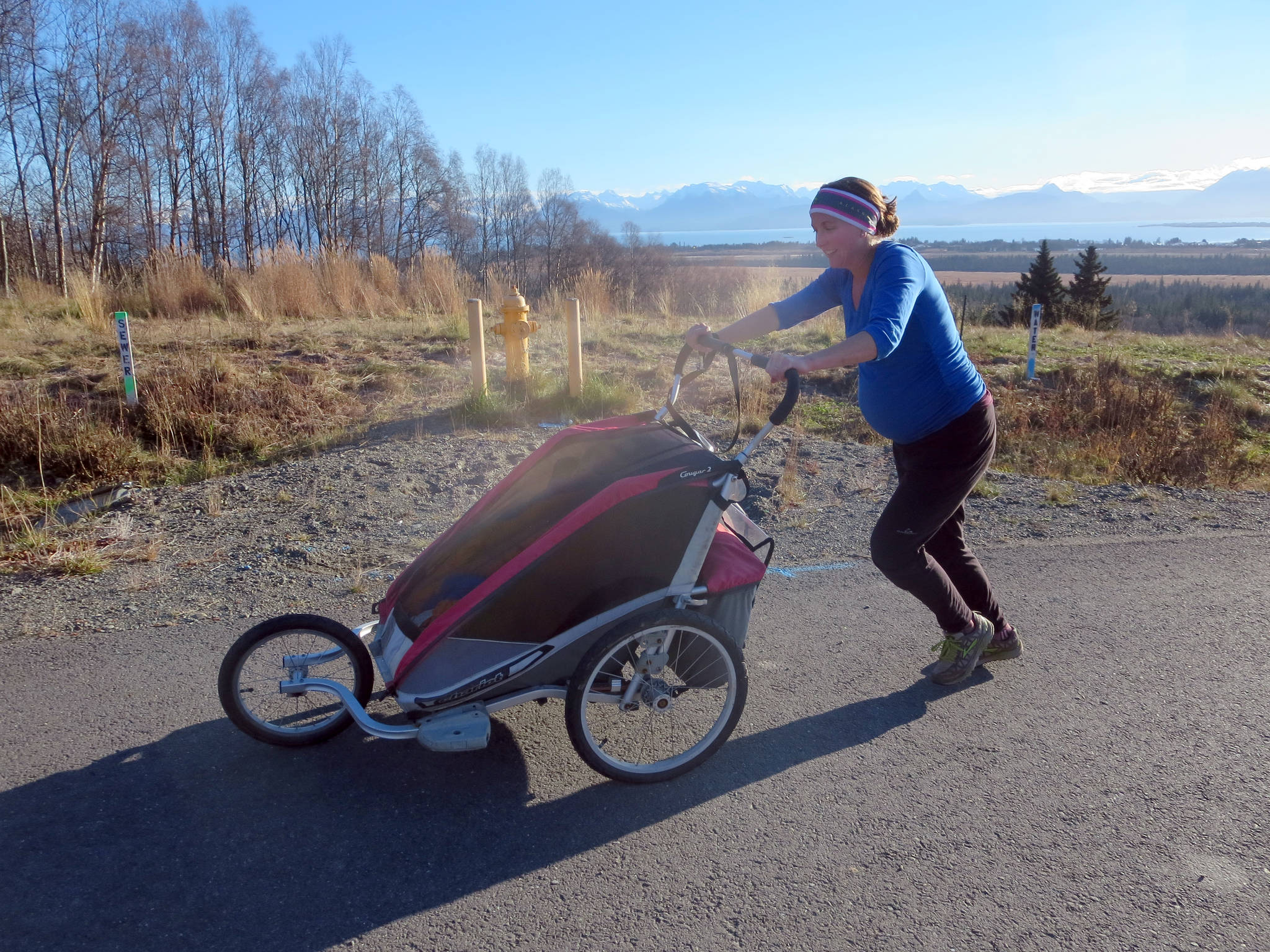 Annie Ridgely trains in 2013 while pregnant, and pushing two children in a stroller up a road at Stream Hill Park. (Photo by Megan Corazza)