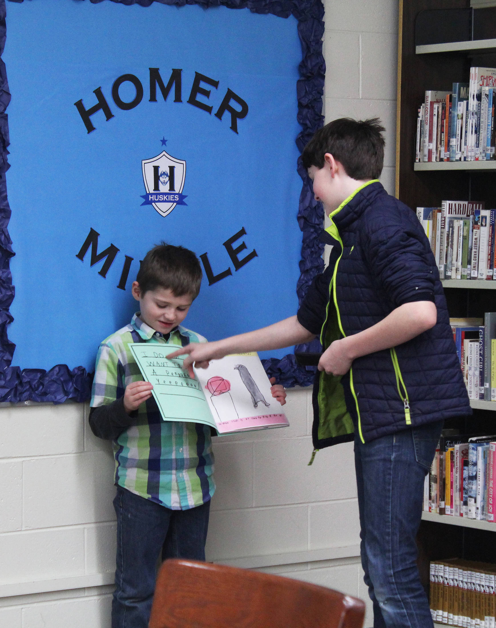 Homer Middle School seventh grader Benjamin Dinges helps Paul Banks Elementary School first grader Adrian Reutov perform a reading of a book they worked on together during a mentor program Friday, Feb. 2, 2018 at Homer Middle School. (Photo by Megan Pacer/Homer News)