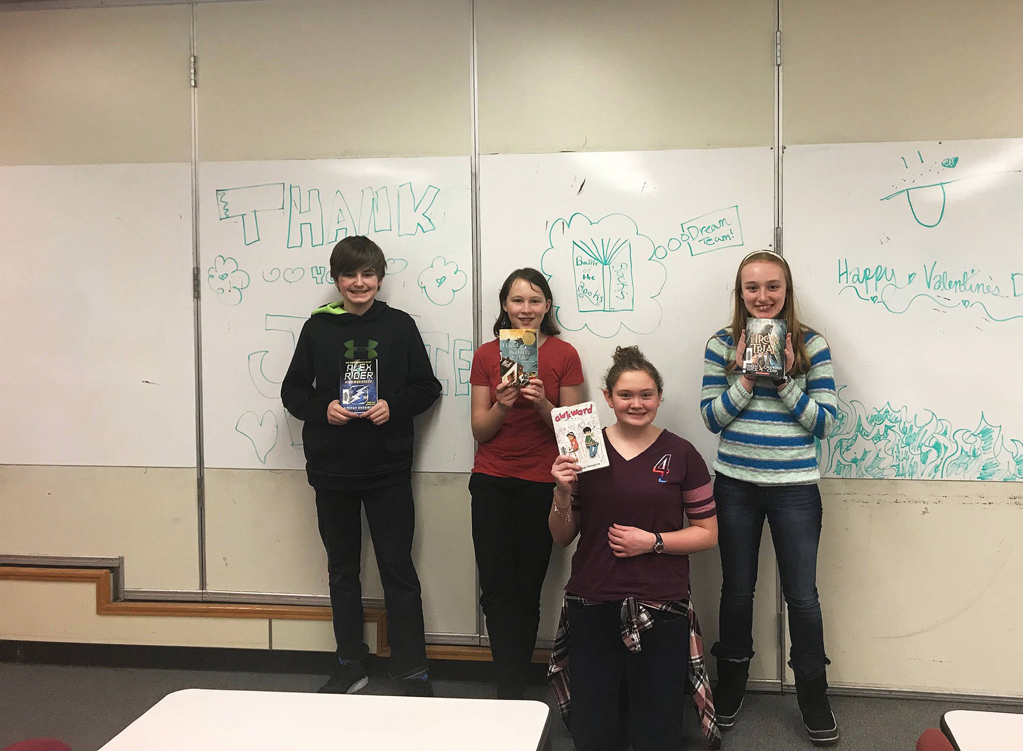 From left to right, Homer Middle School students Tyson Walker, Thea Person, Krystal Super and Lizzy Boyle pose with four of the books they read in preparation for this year’s Battle of the Books competition. The team took first place in their age group and will head to the state competition on Feb. 27. (Photo courtesy Joni Wise)