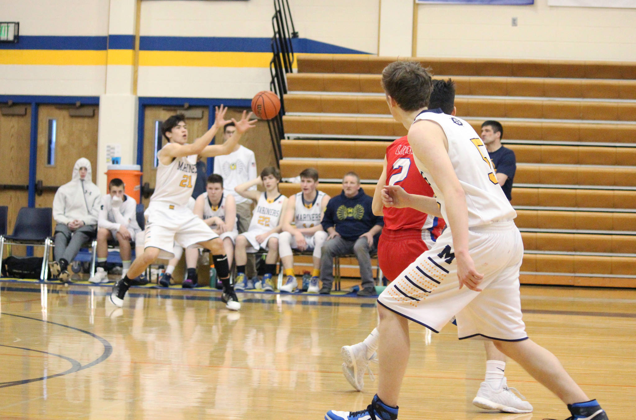 Homer senior Koby Etzwiler (foreground) completes a pass to sophomore Ethan Anderson during their game against Anchorage Christian School on Saturday, Feb. 24, 2018 in the Alice Witte Gymnasium in Homer, Alaska. The Homer basketball teams hosted three schools over the weekend, all at home. (Photo by Megan Pacer/Homer News)