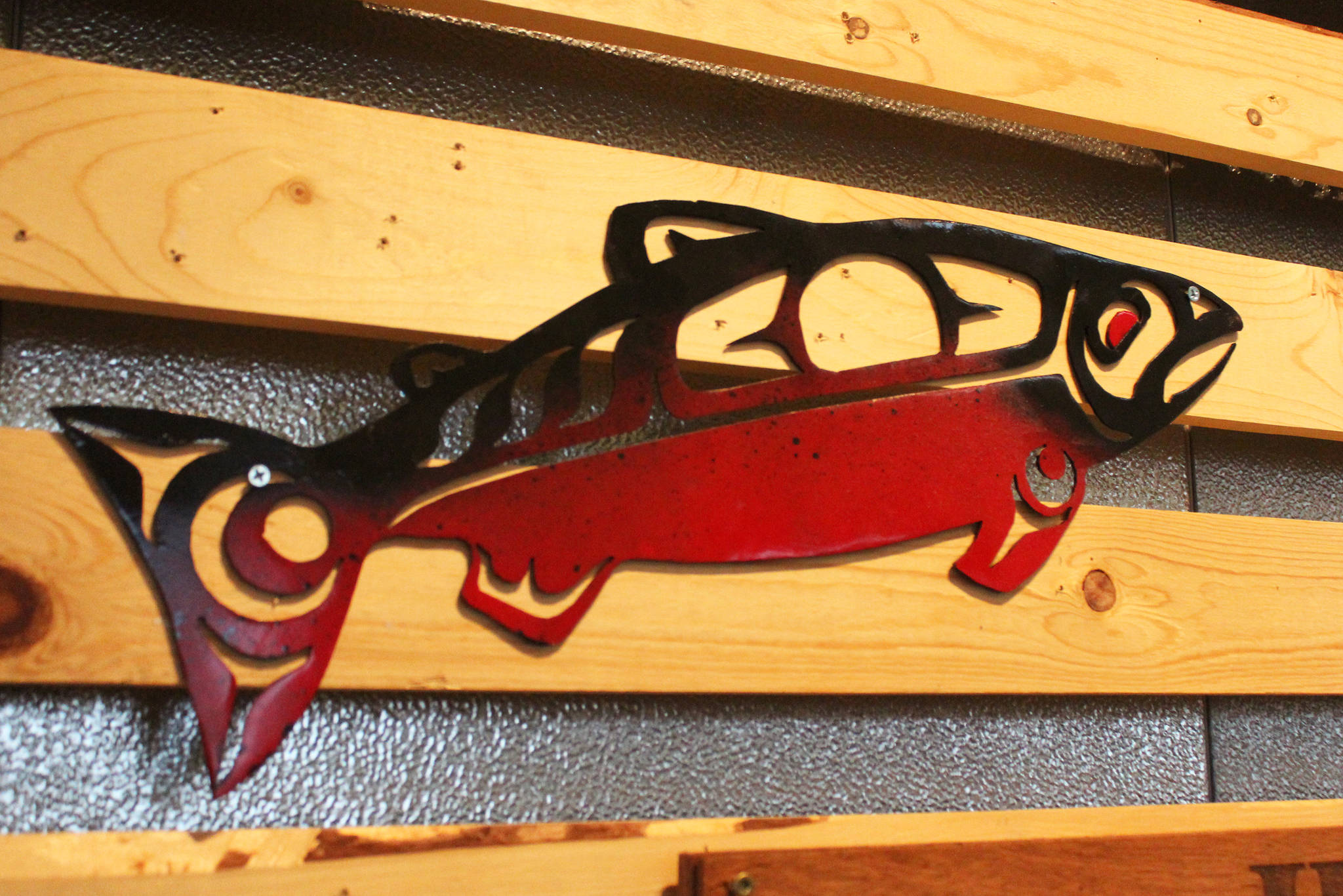 A spraypainted metal fish hangs along with several other creations during a First Friday art show Friday, March 2, 2018 at Grace Ridge Brewery in Homer, Alaska. All the art on display during the show was created by students in Homer High School’s Computer Aided Drafting and Computer Aided Manufacturing program. (Photo by Megan Pacer/Homer News)