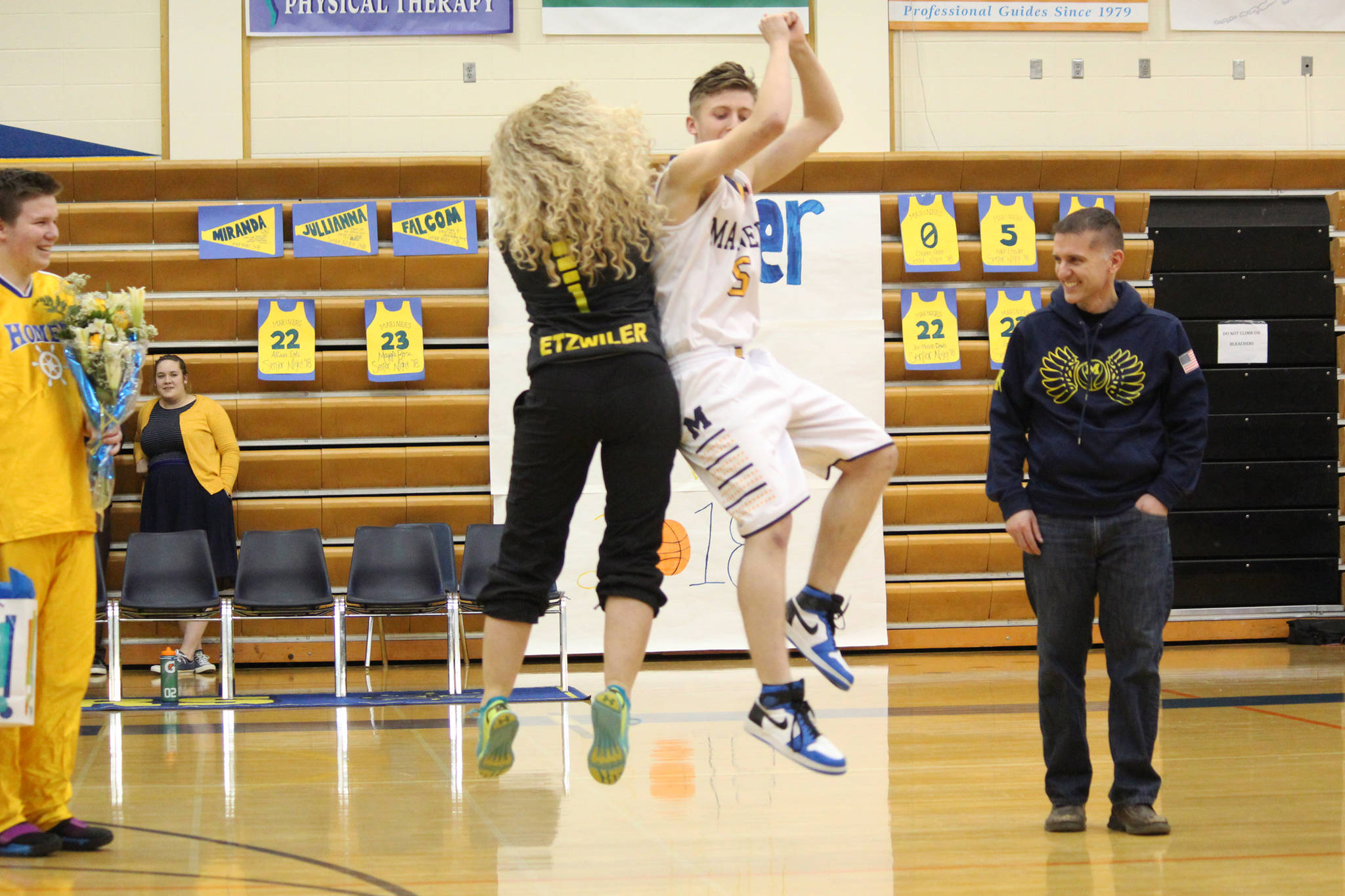 Homer senior Koby Etzwiler jumps into the air with his mother, Krista, in a short a mother-son routine during a Senior Night celebration before the basketball team’s game against Seward on Friday, March 2, 2018 in Homer, Alaska. (Photo by Megan Pacer/Homer News)