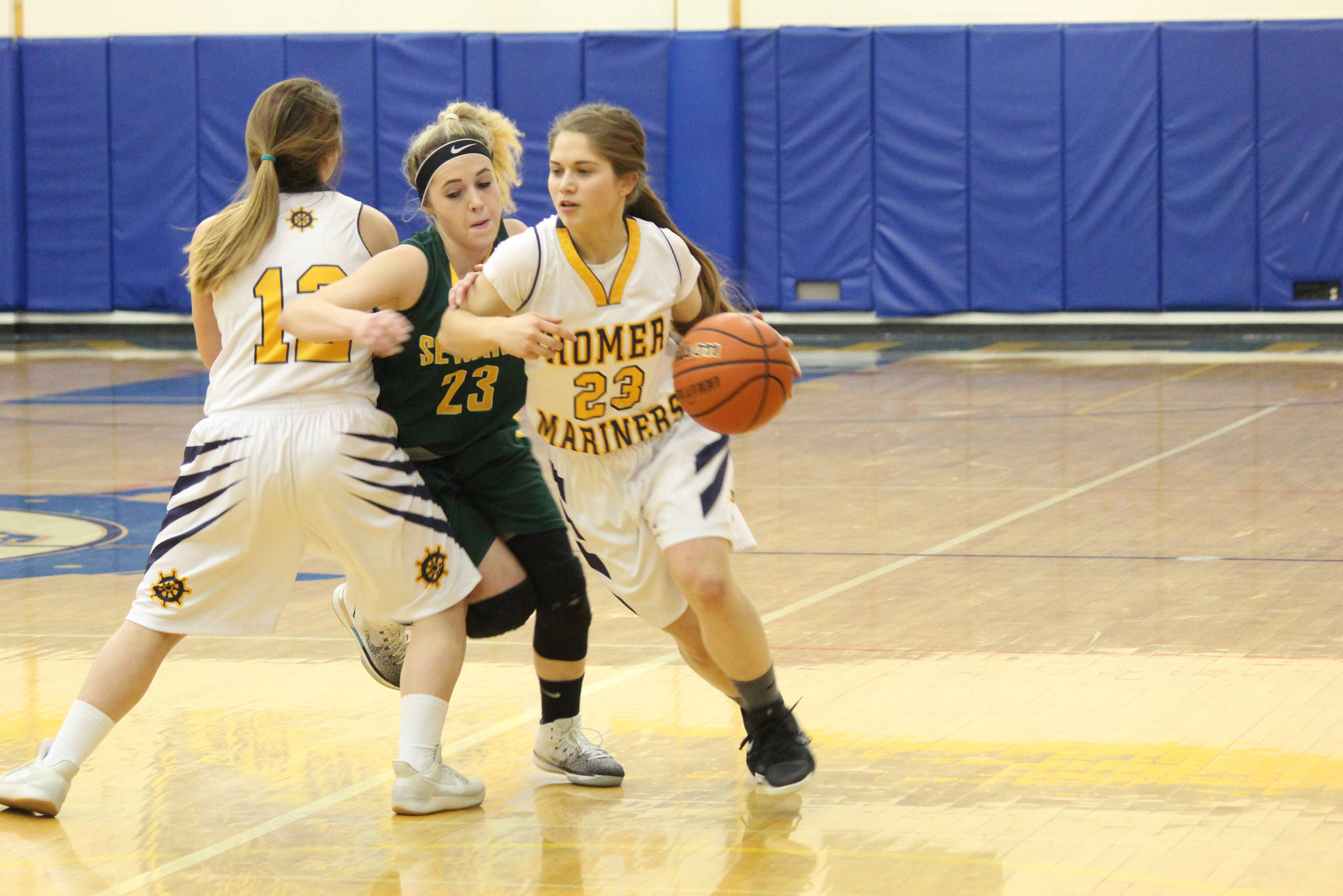 Homer senior Maggie Box, far right, dribbles past a player from Seward High School during their game Friday, March 2, 2018 in Homer, Alaska. Box was one of two senior girls to play their last home game that night. (Photo by Megan Pacer/Homer News)