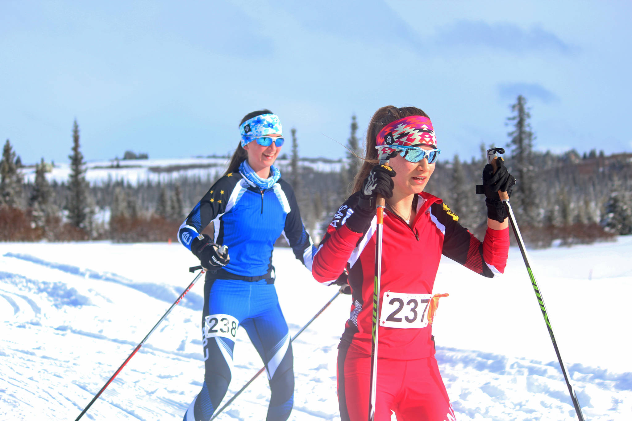 South Anchorage High School students Sadie Oswald, red, and Abby Amick, blue, cross the finish line of the Kachemak Bay Nordic Ski Marathon’s 25 Kilometer race Saturday, March 10, 2018 as the first women across the finish line at the McNeil Canyon Ski Area outside Homer, Alaska. (Photo by Megan Pacer/Homer News)
