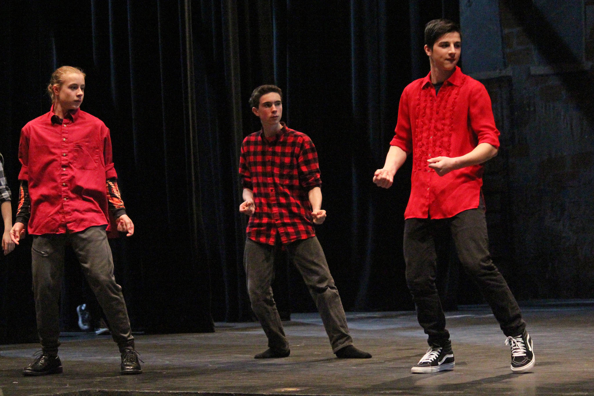 From left to right: Xander Kulhanek, Simon Lopez, and David Weisser perform a dance sequence as members of the Shark gang in “West Side Story” during a dress rehearsal Tuesday, March 20, 2018 at the Mariner Theatre in Homer, Alaska. The musical is this year’s production for the school’s Concert Choir class, and and was last performed by the high school 15 years ago. (Photo by Megan Pacer/Homer News)