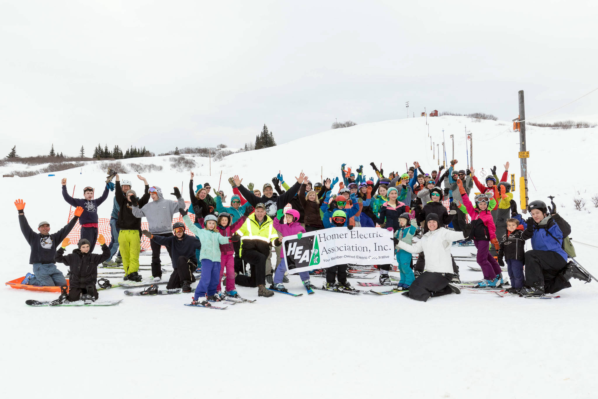 Skiers and snowboarders pose for a photo at the Ohlson Mountain Rope Tow on Sunday, March 18, 2018 for Homer Electric Association Day just outside of Homer, Alaska. HEA Day recognizes the partnership and support of HEA with the Kachemak Nordic Ski Club. (Photo by Don Pitcher)