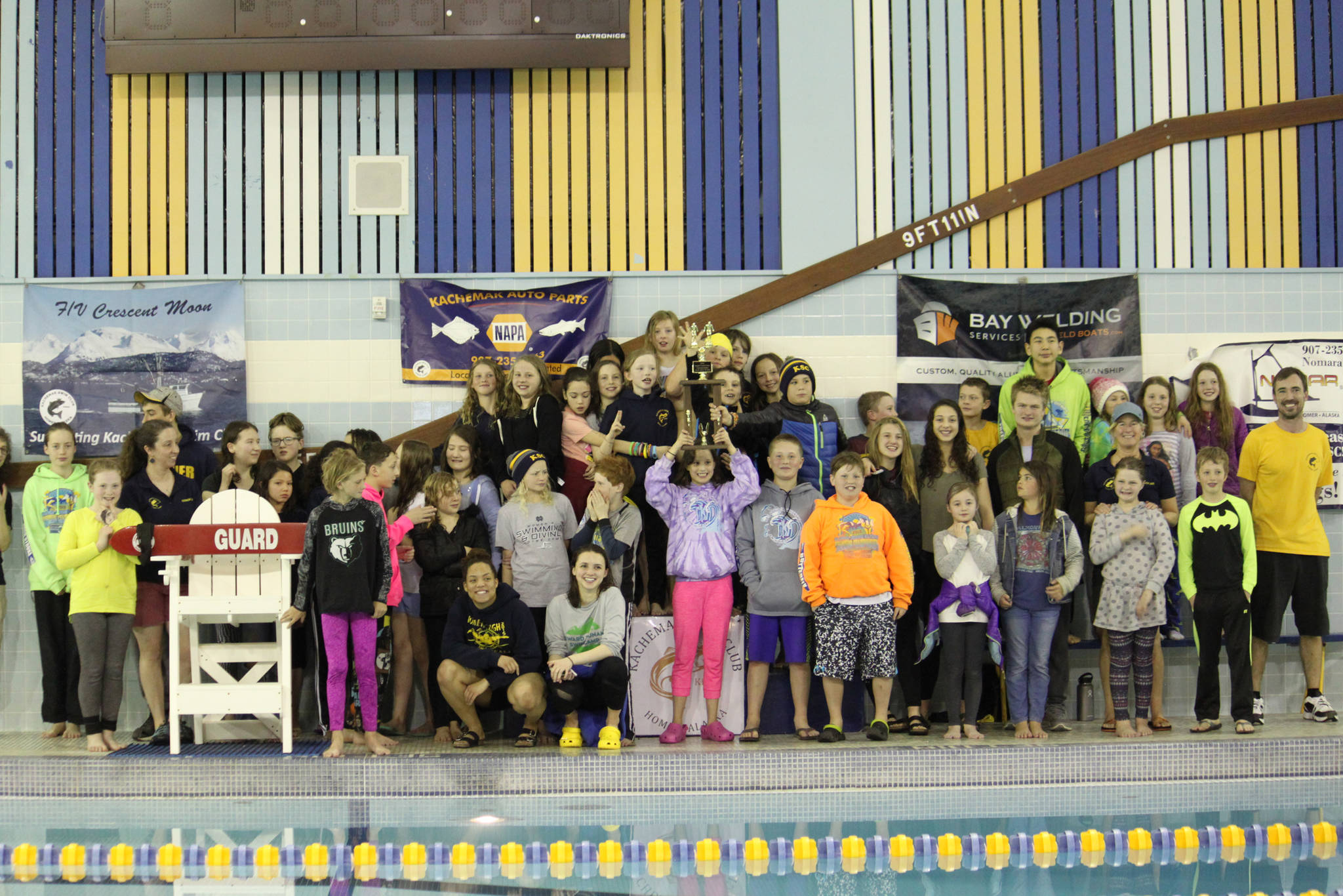 Photo by Monica Anderson Members of the Kachemak Swim Club pose with their first place trophy after an invitational meet they hosted Friday and Saturday, April 6-7 at the Kate Kuhns Aquatic Center in Homer.