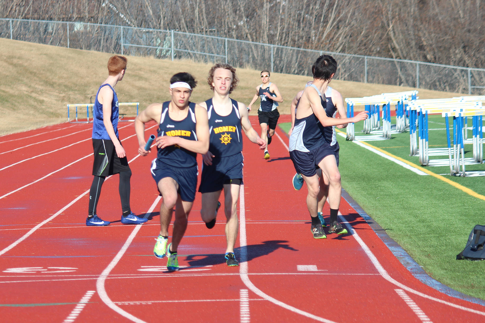 Homer’s Luciano Fasulo takes a handoff from senior Jacob Davis during the boys’ 1,600-meter relay Friday, April 13, 2018 at Homer High School in Homer, Alaska. (Photo by Megan Pacer/Homer News)