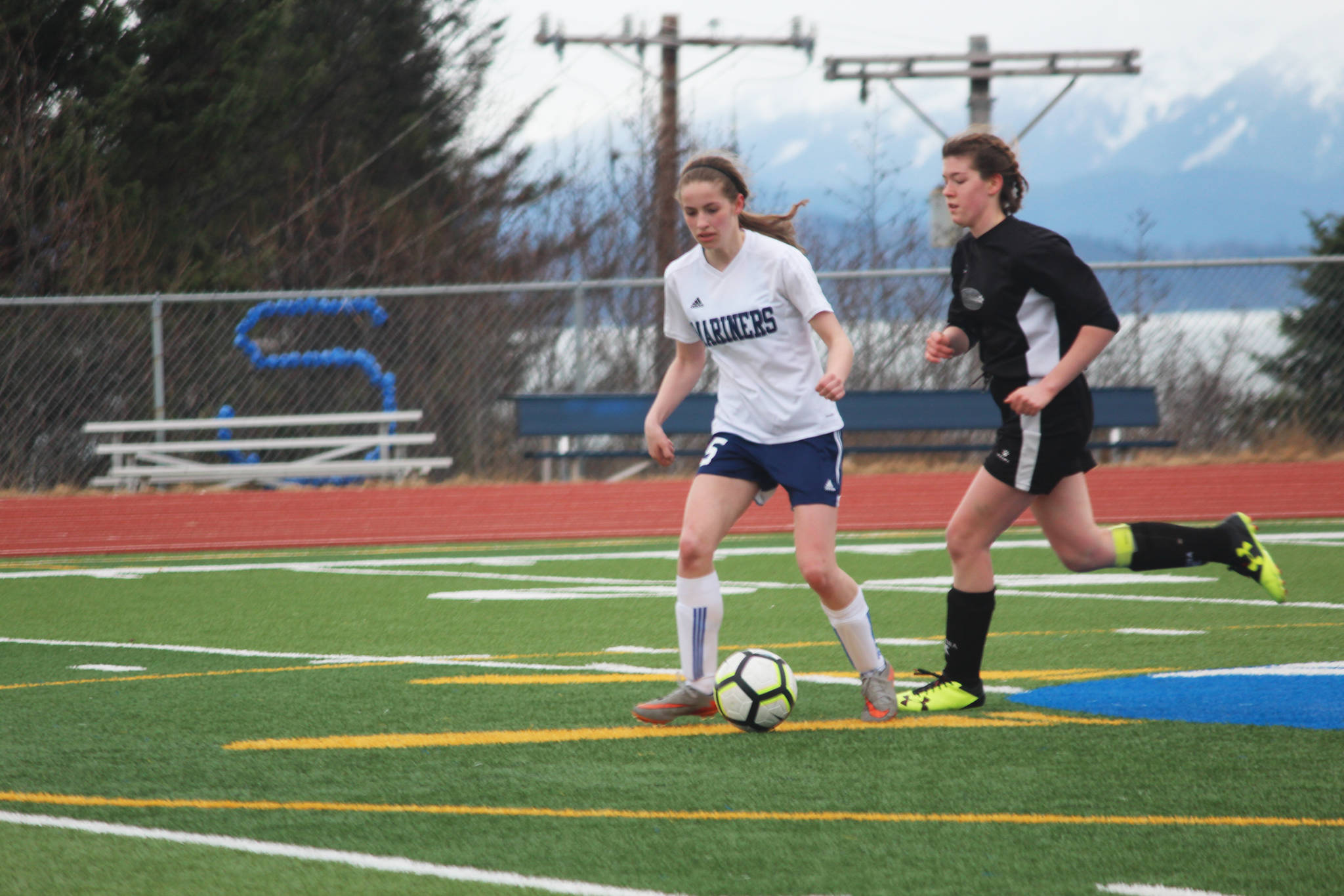 Homer’s Laura Inama keeps the ball away from a Nikiski player during the varsity girls game at home Tuesday, April 17, 2018 in Homer, Alaska. The Mariners swept the Bulldogs 3-0. (Photo by Megan Pacer/Homer News)