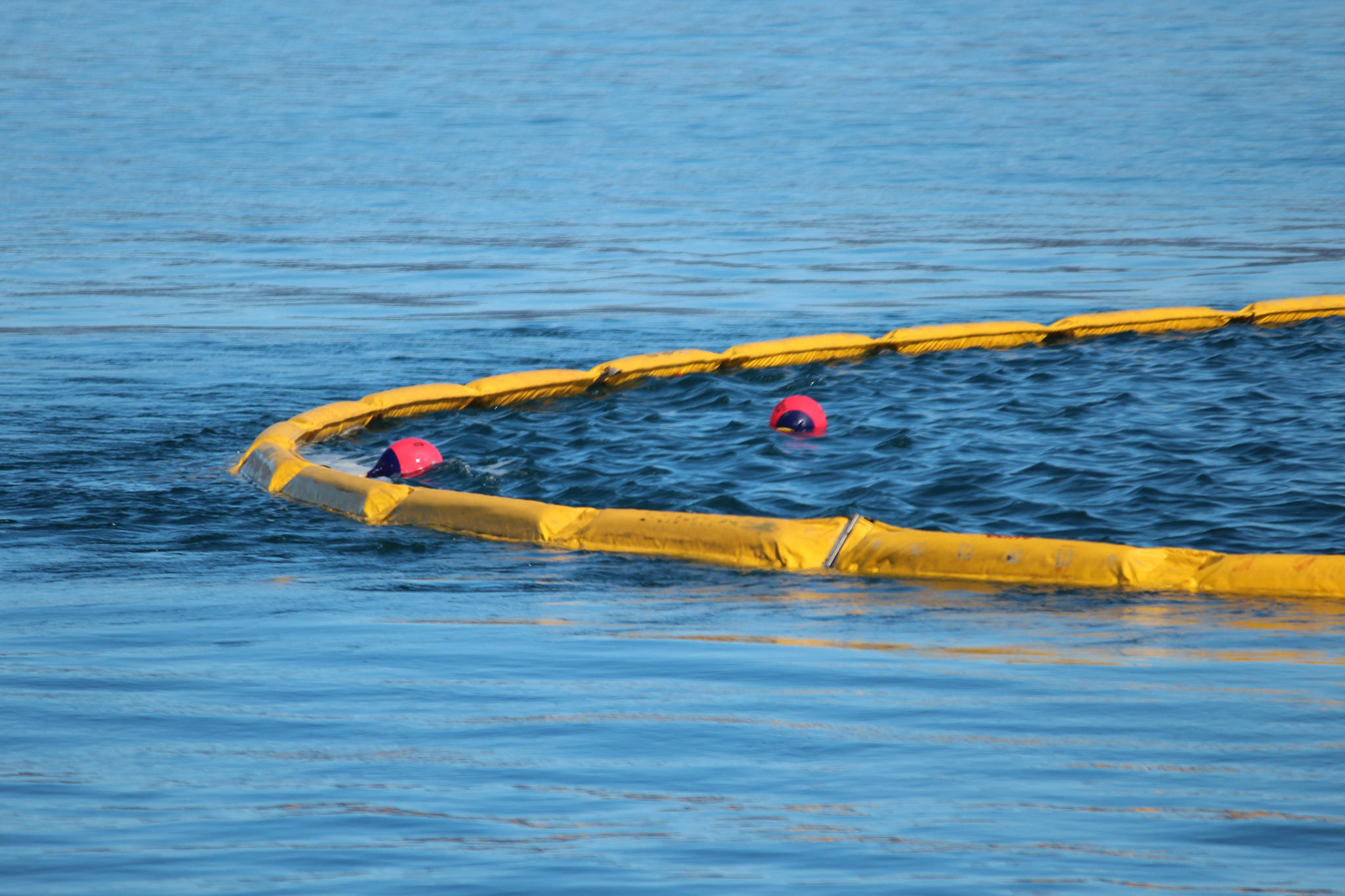 The apex of a boom holds two buoys placed in the water to simulate areas of oil slick fishing vessels needed to aim for during annual oil spill response training held Saturday, April 14, 2018 in Homer, Alaska. Vessels need to tow boom slowly to avoid turbulent water at the apex of the boom, which can allow oil to slip out the back. (Photo by Megan Pacer/Homer News)