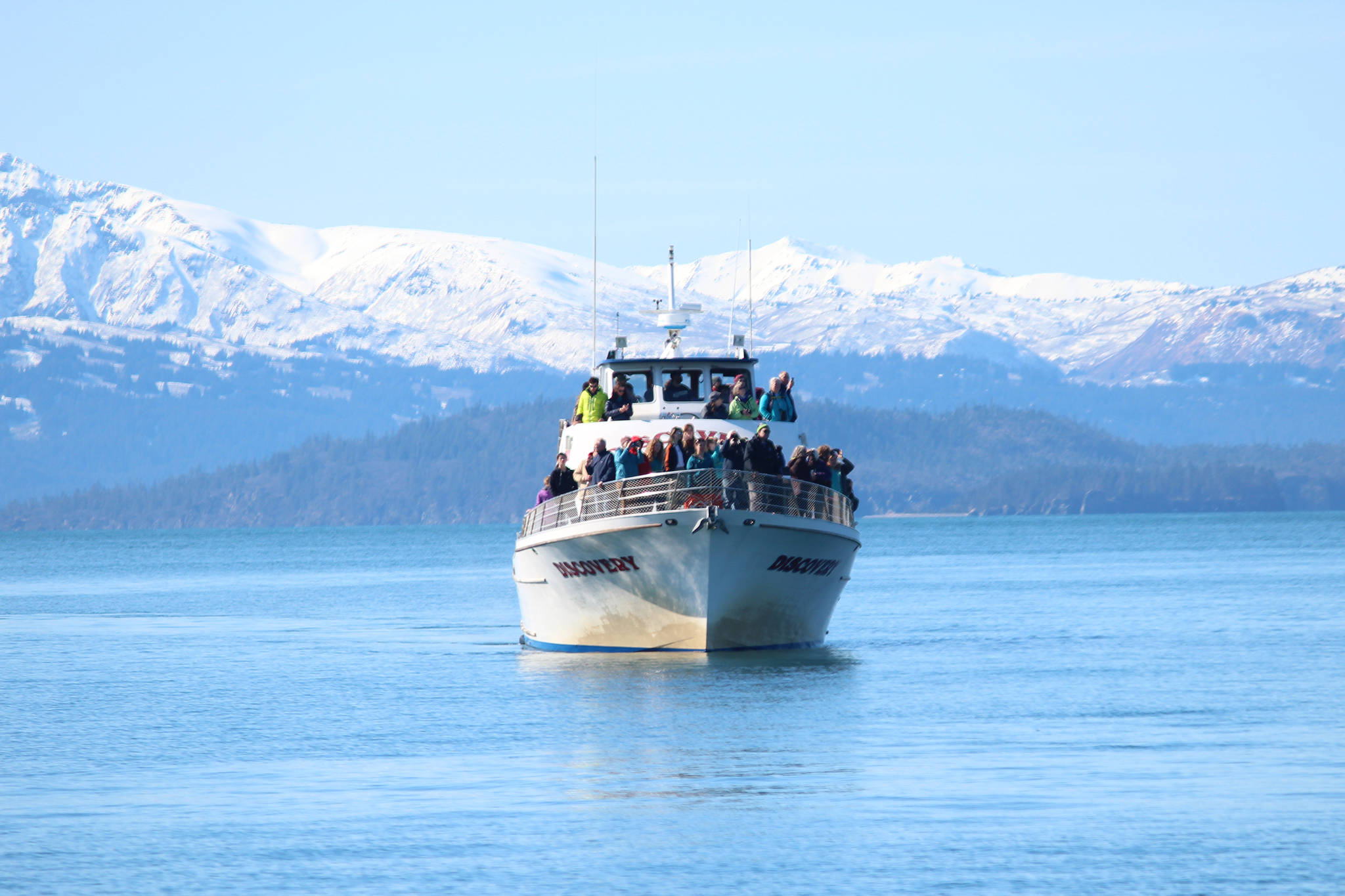 Residents of the Homer area peer off the bow of the Discovery during a tour of oil spill response training hosted by the Prince William Sound Regional Citizens’ Advisory Council in conjunction with Alyeska Pipeline, Alaska Coastal Marine and the Center for Alaskan Coastal Studies, on Saturday, April 14, 2018 in Homer, Alaska. Residents aboard two boats were taken across Kachemak Bay for an up close look at how fishing vessels train annually for the event of an oil spill. (Photo by Megan Pacer/Homer News)
