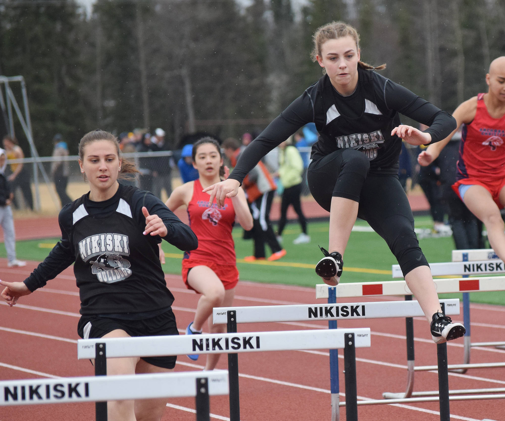 Nikiski teammates Kelsey Clark (left) and Bethany Carstens hurdle a barrier in the girls 300-meter hurdles Saturday at the Kenai Invitational at Ed Hollier Field. (Photo by Joey Klecka/Peninsula Clarion)