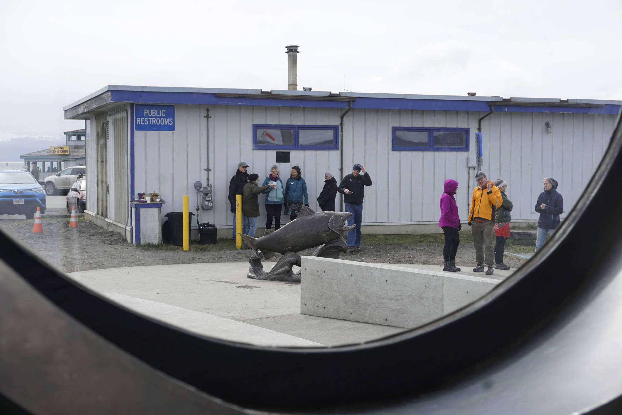 Wildheart, the Giving Salmon sculpture, and the Ramp 2 restroom are framed in a window of the Boat House Saturday, May 12, 2018 at the Homer Harbor. (Photo by Michael Armstrong/Homer News)