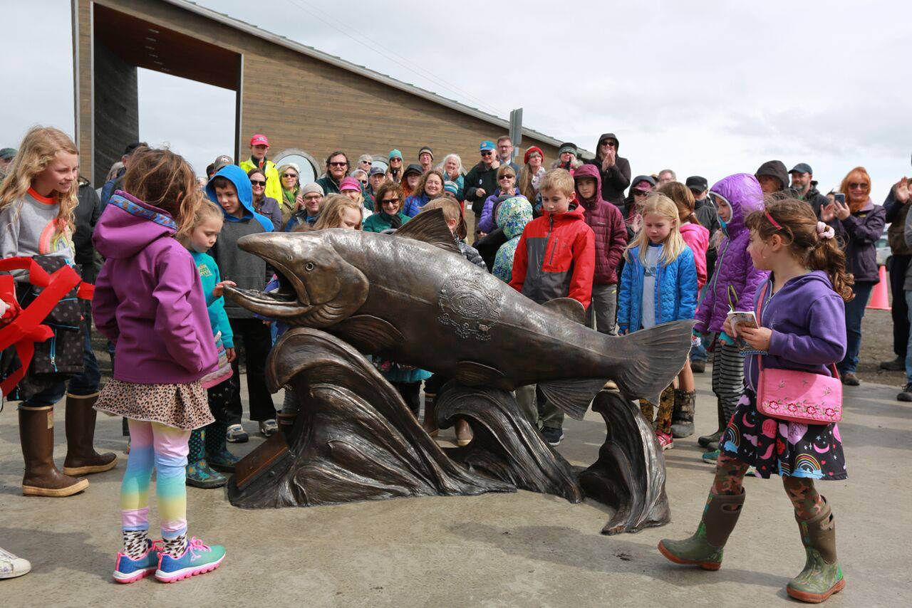 Children gather around Wildheart, the Giving Salmon, sculpture last Saturday at the ribbon cutting for the Homer Boat House. Christina Demetro of Anchorage created the sculpture with assistance from Homer community members, including children. (Photo by Kathyrn Henry)
