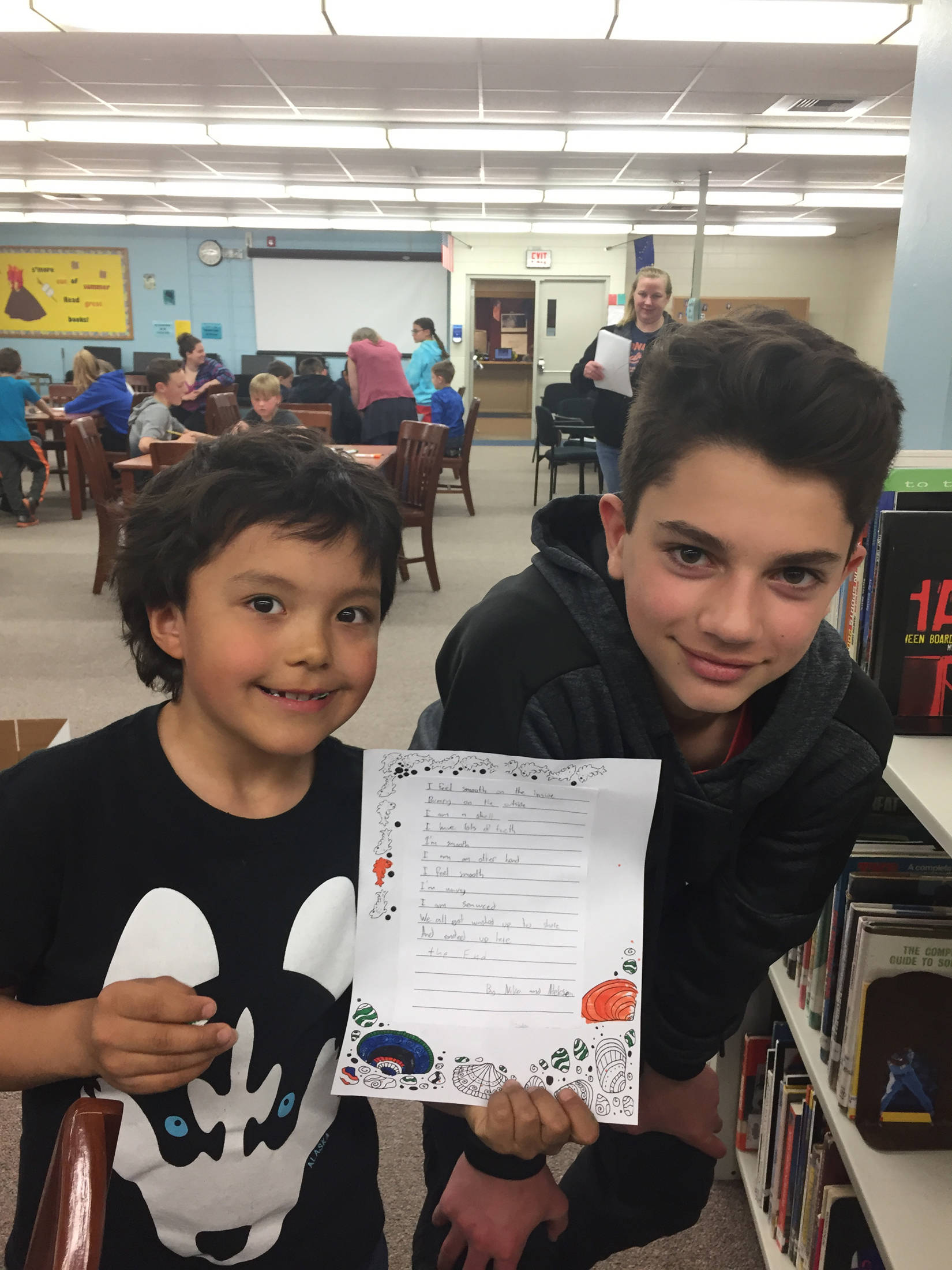Niko Sulczynski (right) and his partner Aleksea Yatchmeneff (left) show off their finished poem during the last mentoring meeting between students from Paul Banks Elementary and Homer Middle School on Monday, May 14, 2018 at the middle school in Homer, Alaska. (Photo provided)