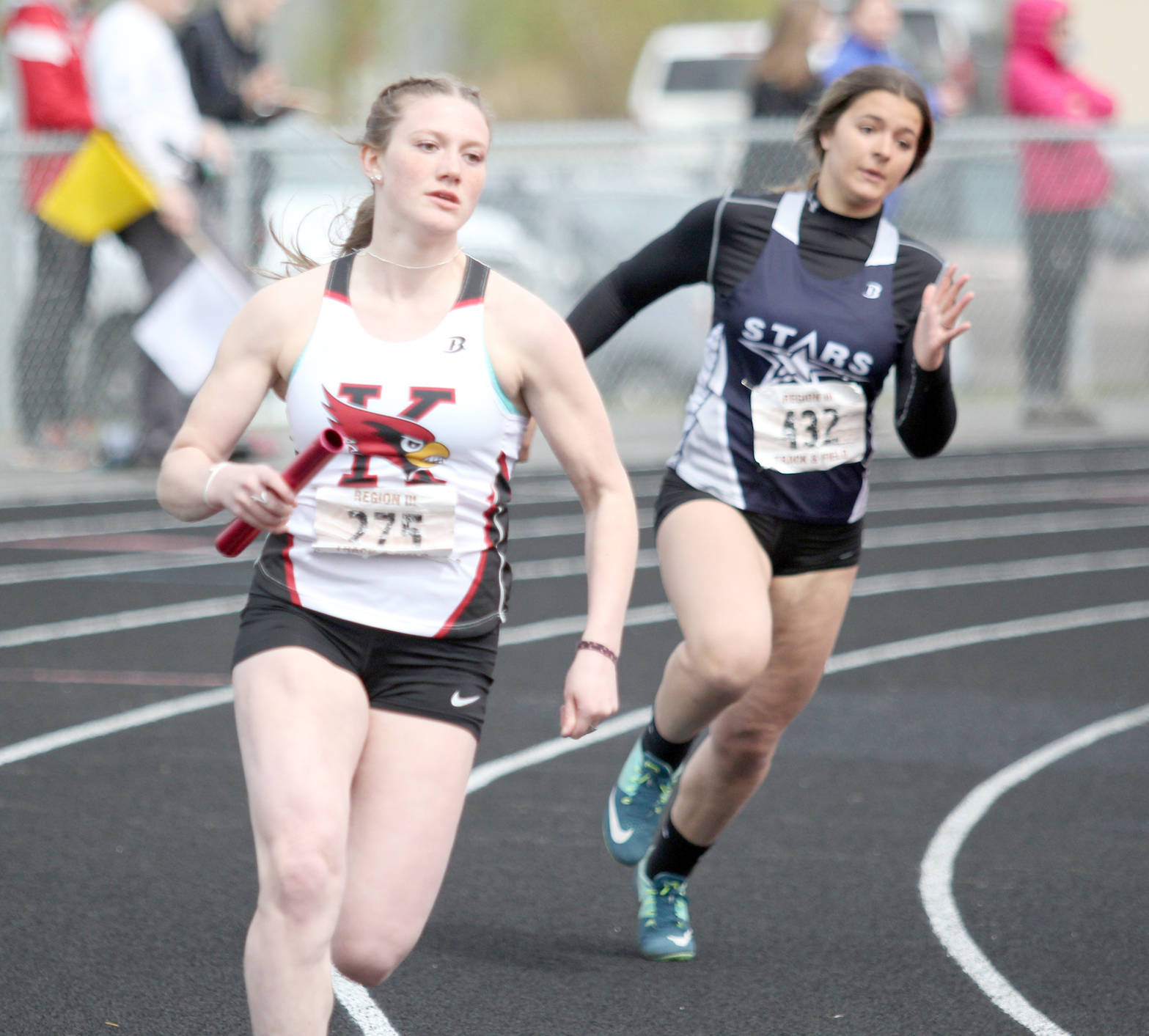 Kenai Central’s Addison Gibson and Mikayla Leadens of Soldotna compete in the 800-meter relay Saturday, May 19, 2018, at Houston High School. (Photo by Jeremiah Bartz/Frontiersman.com)