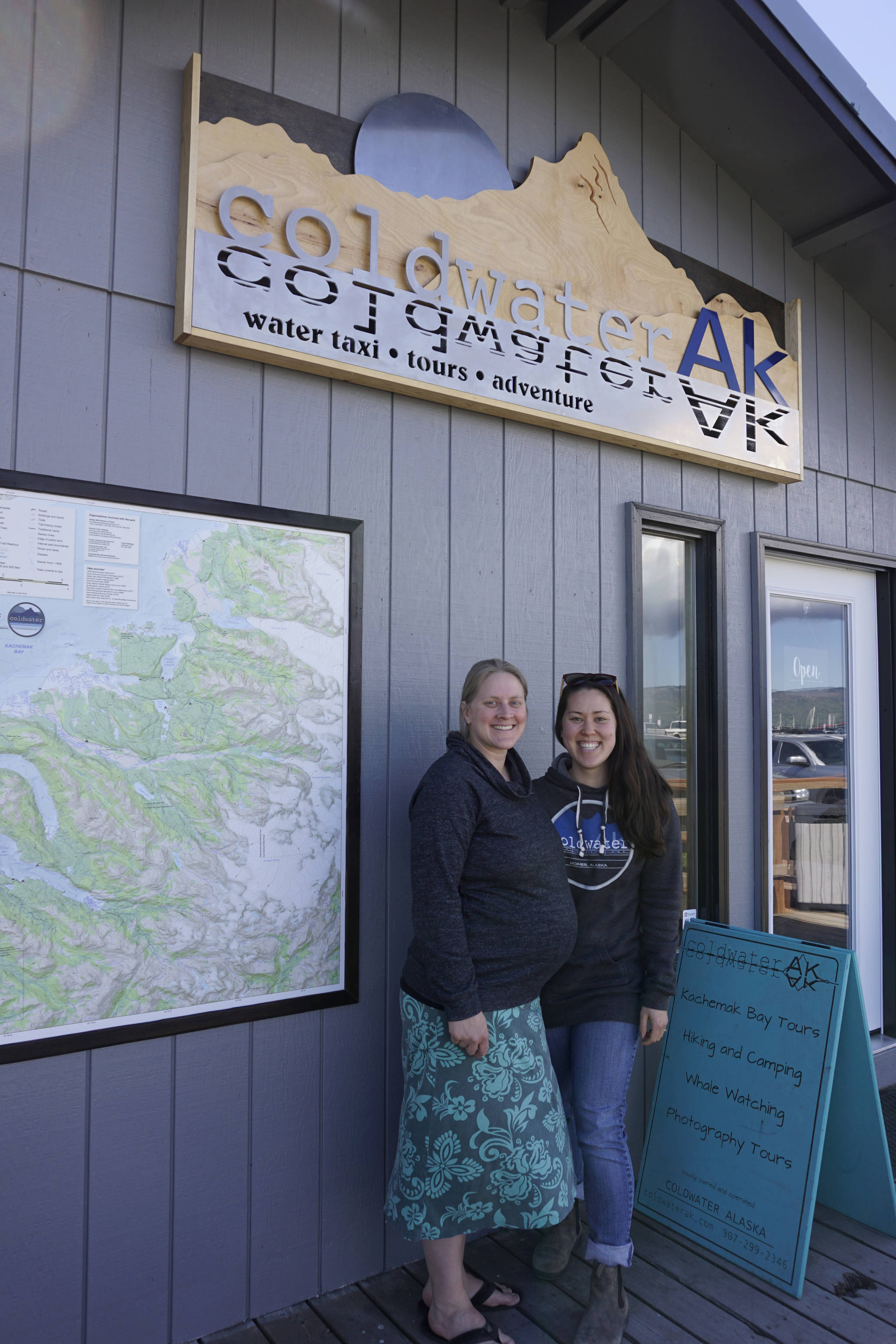 Lisa Conley, left, and Soniyae Reid, right, on Friday, June 1, 2018, stand outside the new offices of Coldwater AK water taxi and tour company in the Centra Charters Boardwalk on the Homer Spit.