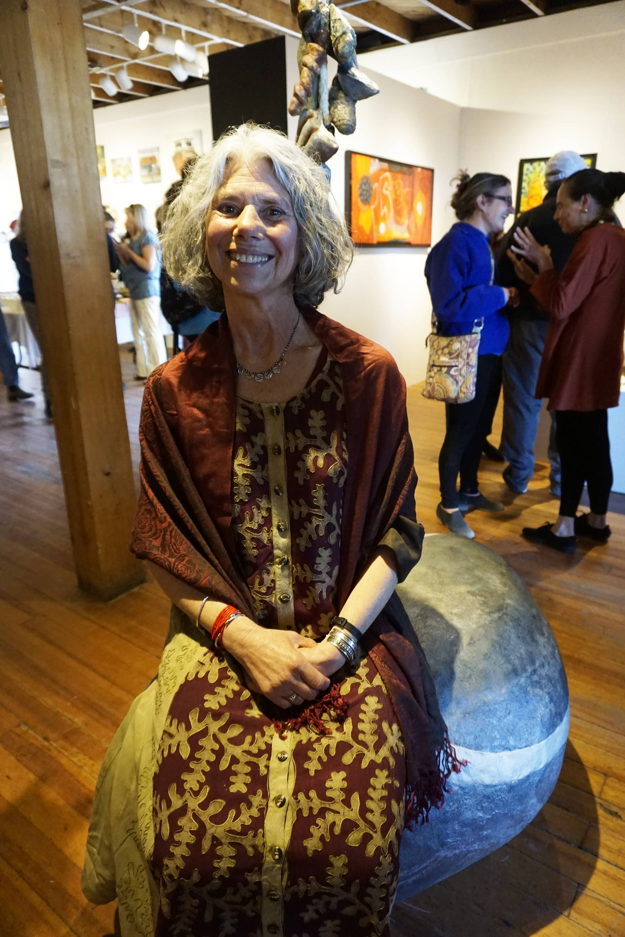 Photo by Michael Armstrong/Homer News Melisse Reichman sits on her sculpture, “Pocket Pebble,” at the Friday, June 1 opening of her show at Bunnell Street Arts Center. Anchorage artist Graham Dane also shows his works.