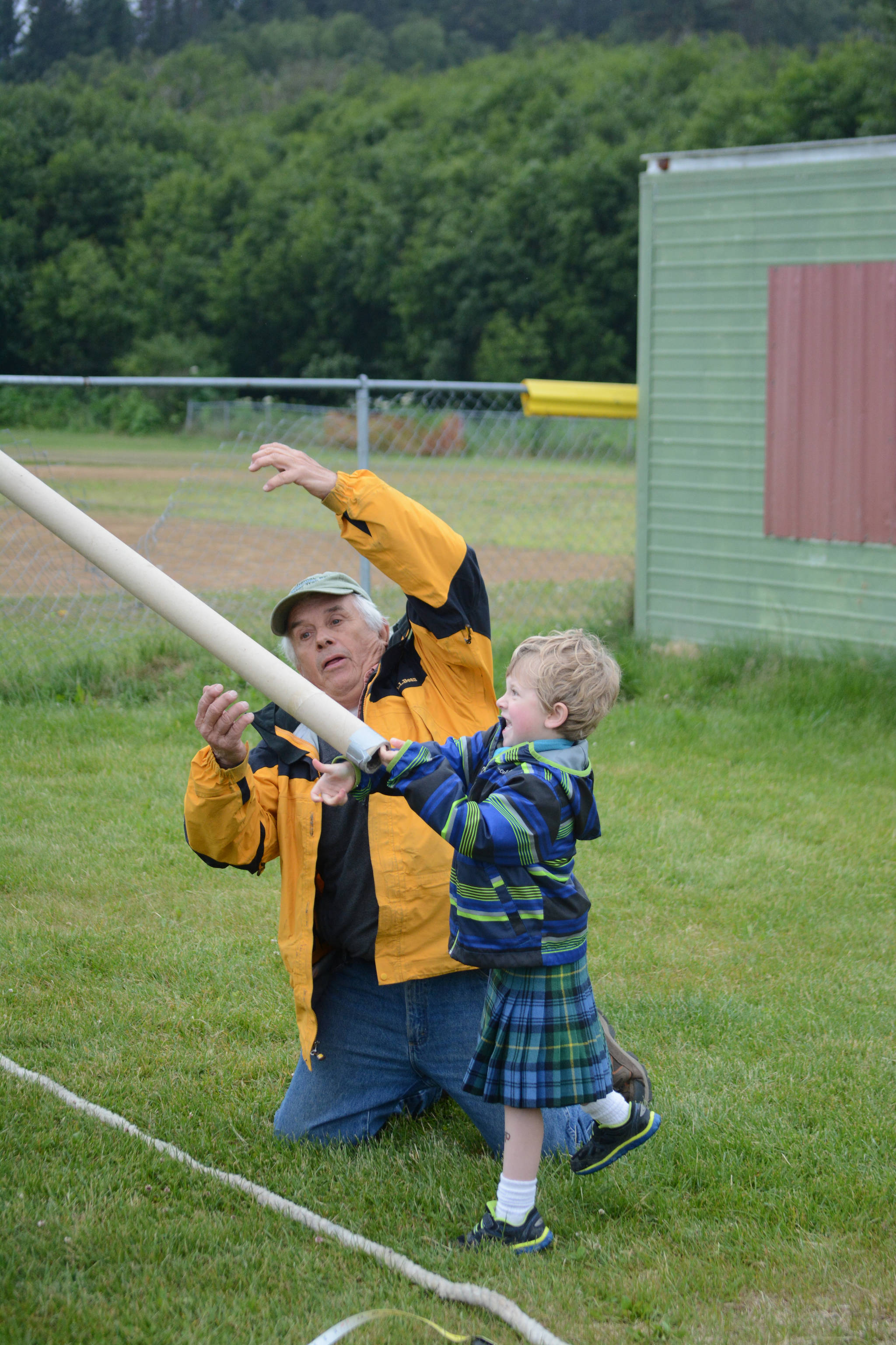 Torrin Bartlett tosses the caber (a cardboard tube) during the children’s events in the July 3, 2017 Kachemak Bay Scottish Club Games at Karen Hornaday Park as Dave Brann, left, watches. (Photo by Michael Armstrong/Homer News)