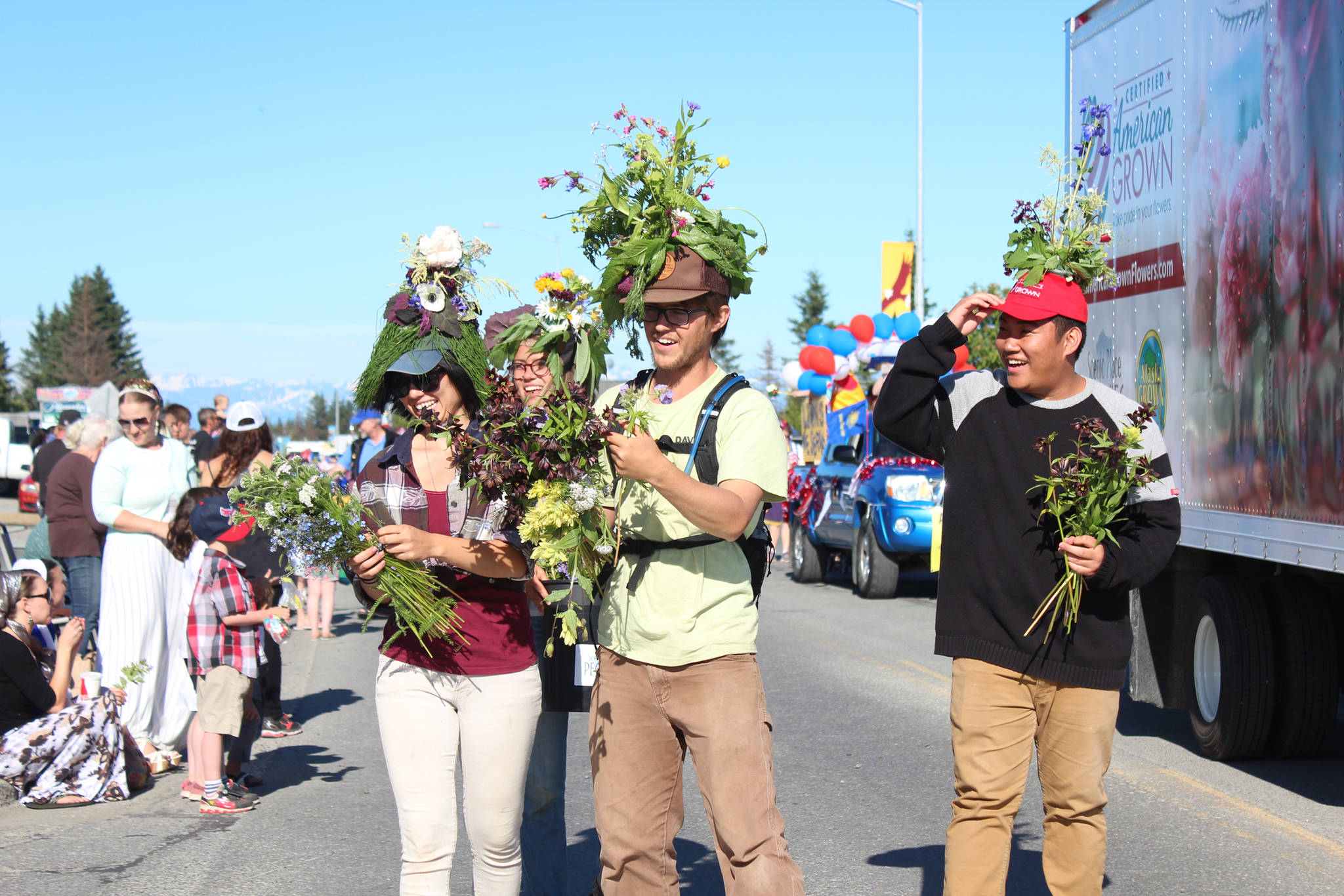 Parade participants marching with a Certified American Grown truck pass out fresh blooms to families lining Pioneer Avenue during the annual Independence Day parade Wednesday, July 4, 2018 in Homer, Alaska. (Photo by Megan Pacer/Homer News)