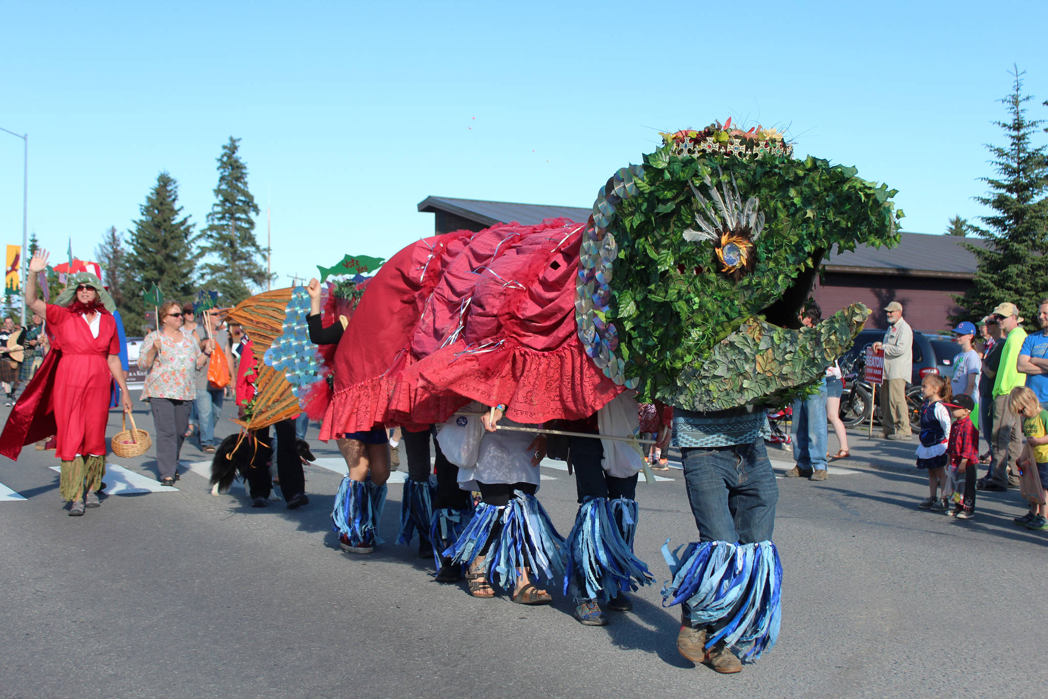 Several people walking down Pioneer Avenue in a giant salmon costume for Cook Inletkeeper’s portion of the Independence Day parade Wednesday, July 4, 2018 in Homer, Alaska. Other participants carried signs promoting the Stand for Salmon initiative. (Photo by Megan Pacer/Homer News)