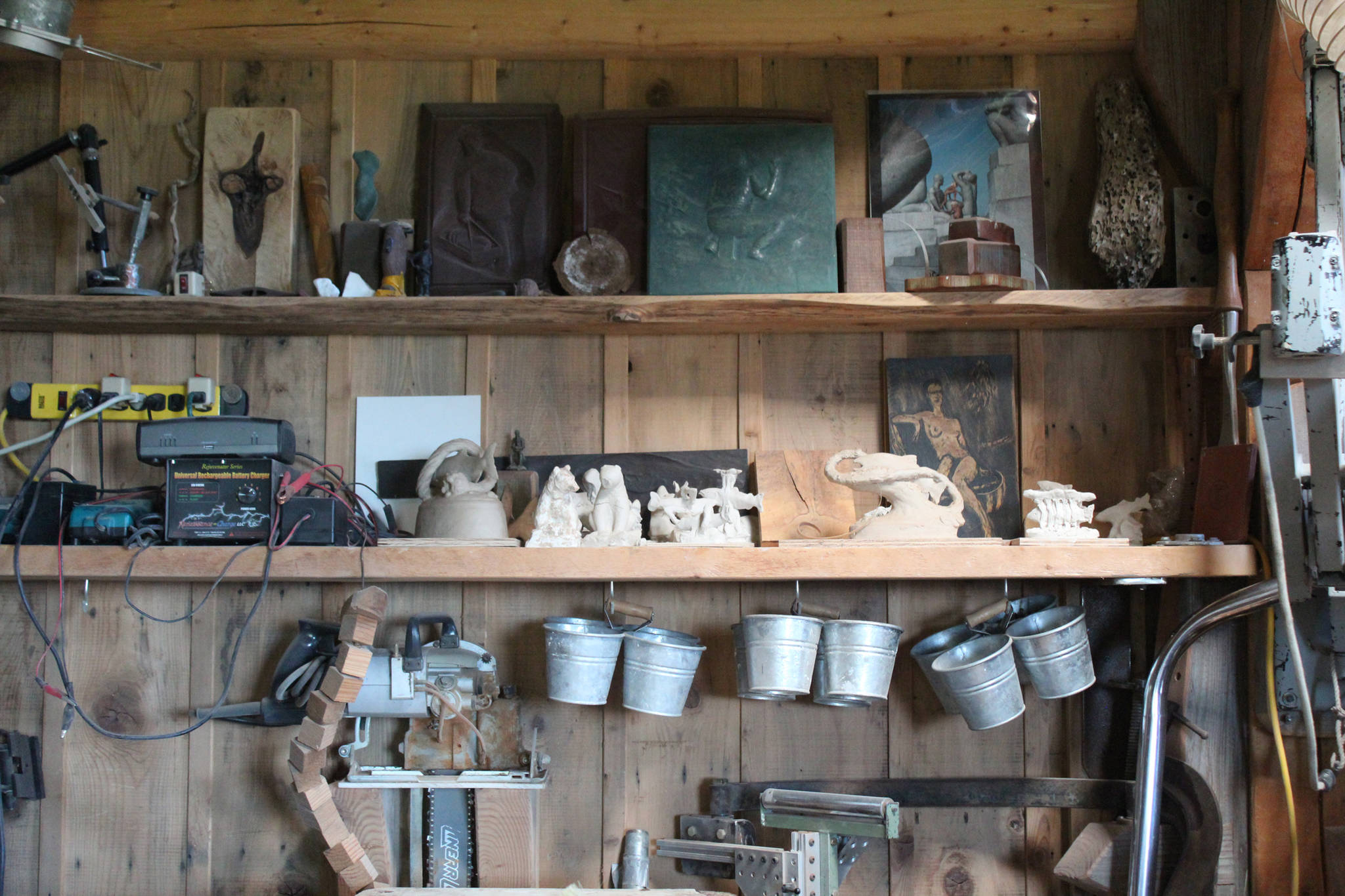 Tools and pieces of art in various stages of completion line the shelves of Jeff and Ranja Dean’s art studio, shown here during a tour Friday, July 6, 2018 at their home off East End Road near Homer, Alaska. (Photo by Megan Pacer/Homer News)