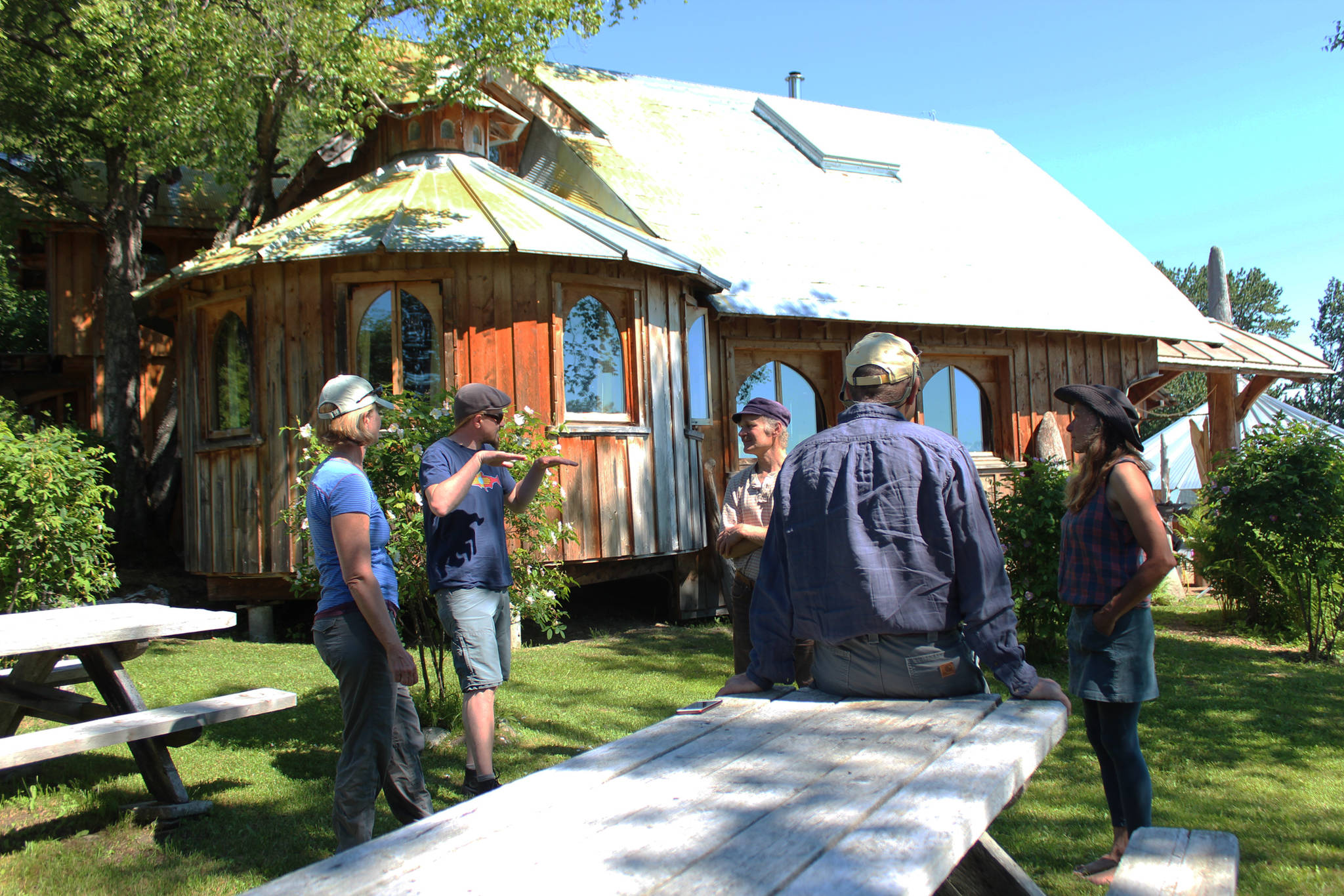 From left to right: Leah Evans Cloud, Jonah Cloud, Jeff Dean, Brad Thornburgh and Ranja Dean chat outside the Deans’ home down East End Road before a tour on Friday, July 6, 2018 near Homer, Alaska. The Deans open their farm and art studios to interested visitors. (Photo by Megan Pacer/Homer News)