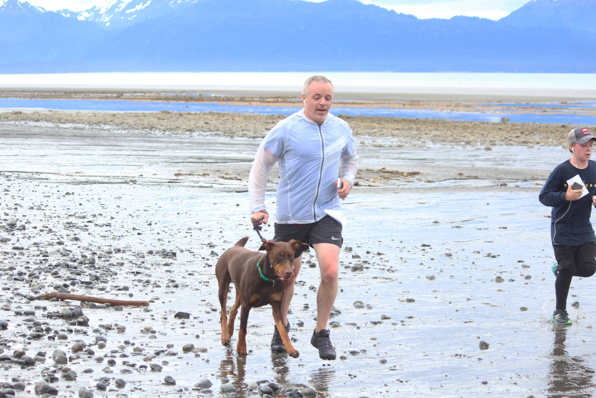 A runner approaches the finish line of the Chariots of Fur 5K with his dog on Saturday, July 14, 2018 near Mariner Park in Homer, Alaska. (Photo by Megan Pacer/Homer News)