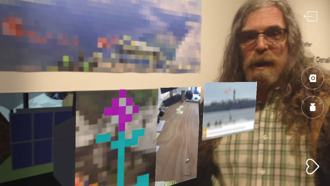 Images from the “Dirigibles of Denali” show at the Pratt Museum appear when viewed through the HP Reveal augmented reality app, as seen through a screen capture on an iPhone. The augmented reality images appear in front of artist Brian Payne as he stands by one display at the July 6, 2018 First Friday opening in Homer, Alaska. (Photo by Michael Armstrong/Homer News)