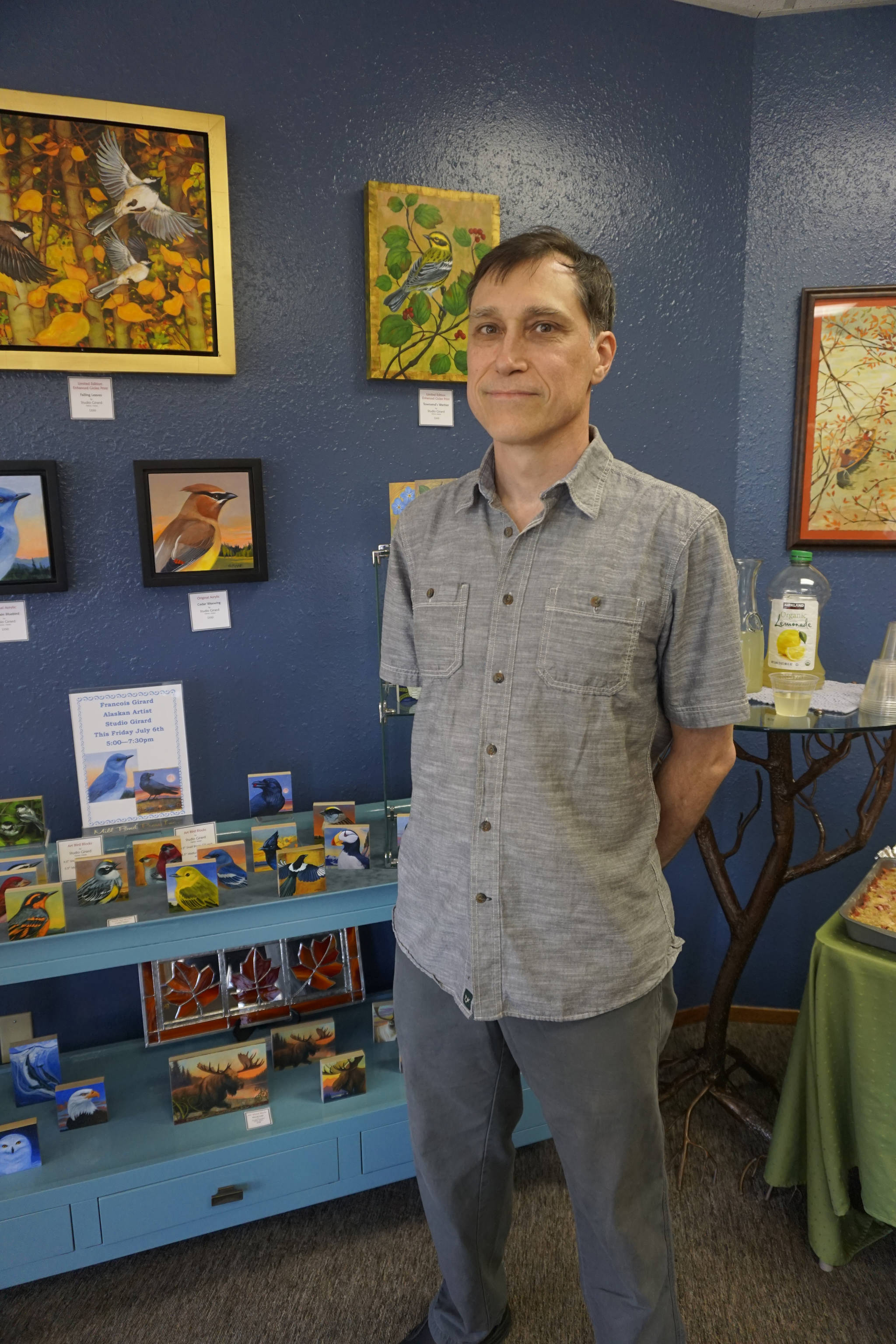 Bird is the word Palmer artist Francois Girard stands by art from his show, “Alaska Wings,” at the First Friday opening on July 6 at the Art Shop Gallery in Homer, Alaska. Girard creates sculptures he calls “Bird Blocks” made from prints adhered to wood and varnished. He also displays some of his original paintings. (Photo by Michael Armstrong/Homer News)